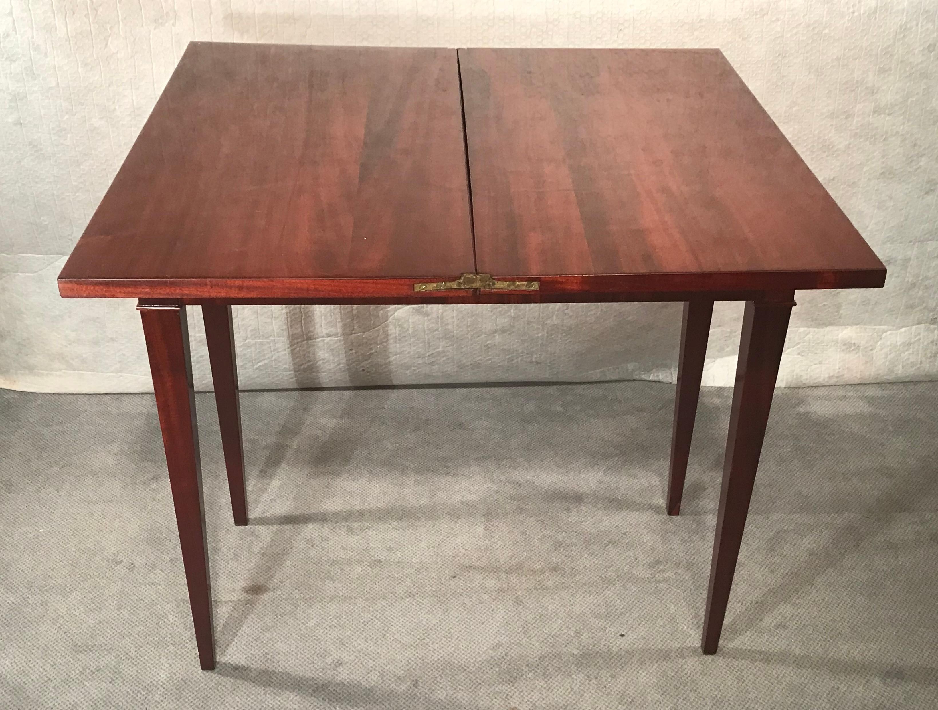 This French Directoire card table dates back to around 1800-10, It has a pretty mahogany veneer. The table stands on four pointed legs. The top can be folded out and rests on the pull out apron and legs. It comes refinished. This is a beautiful