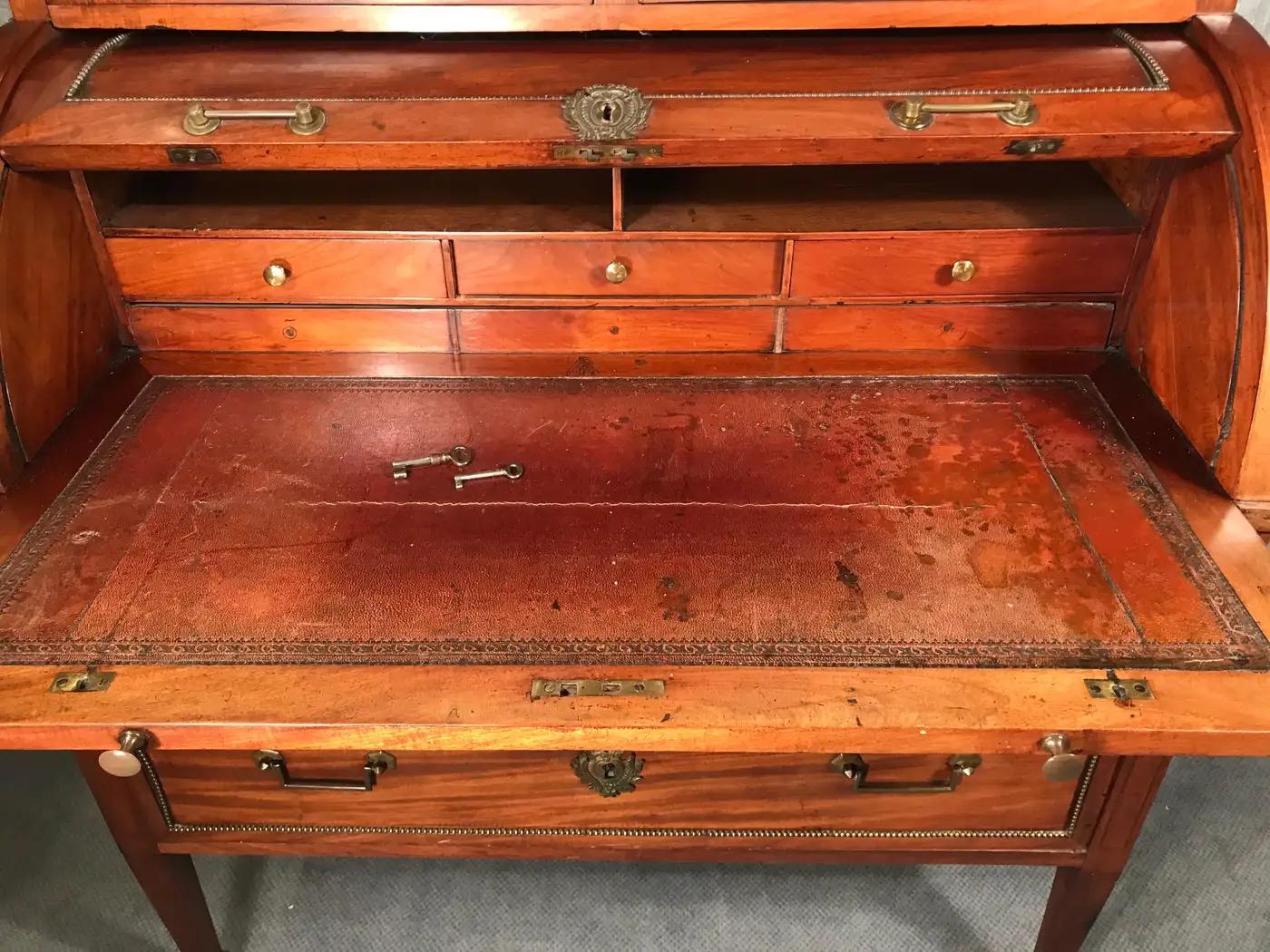 Scrivania a cilindro direttoriale con libreria sul piano, Francia 1800, impiallacciatura di mogano. La scrivania ha i suoi accessori originali in ottone. Anche la pelle della superficie di scrittura è originale. La superficie della scrivania può