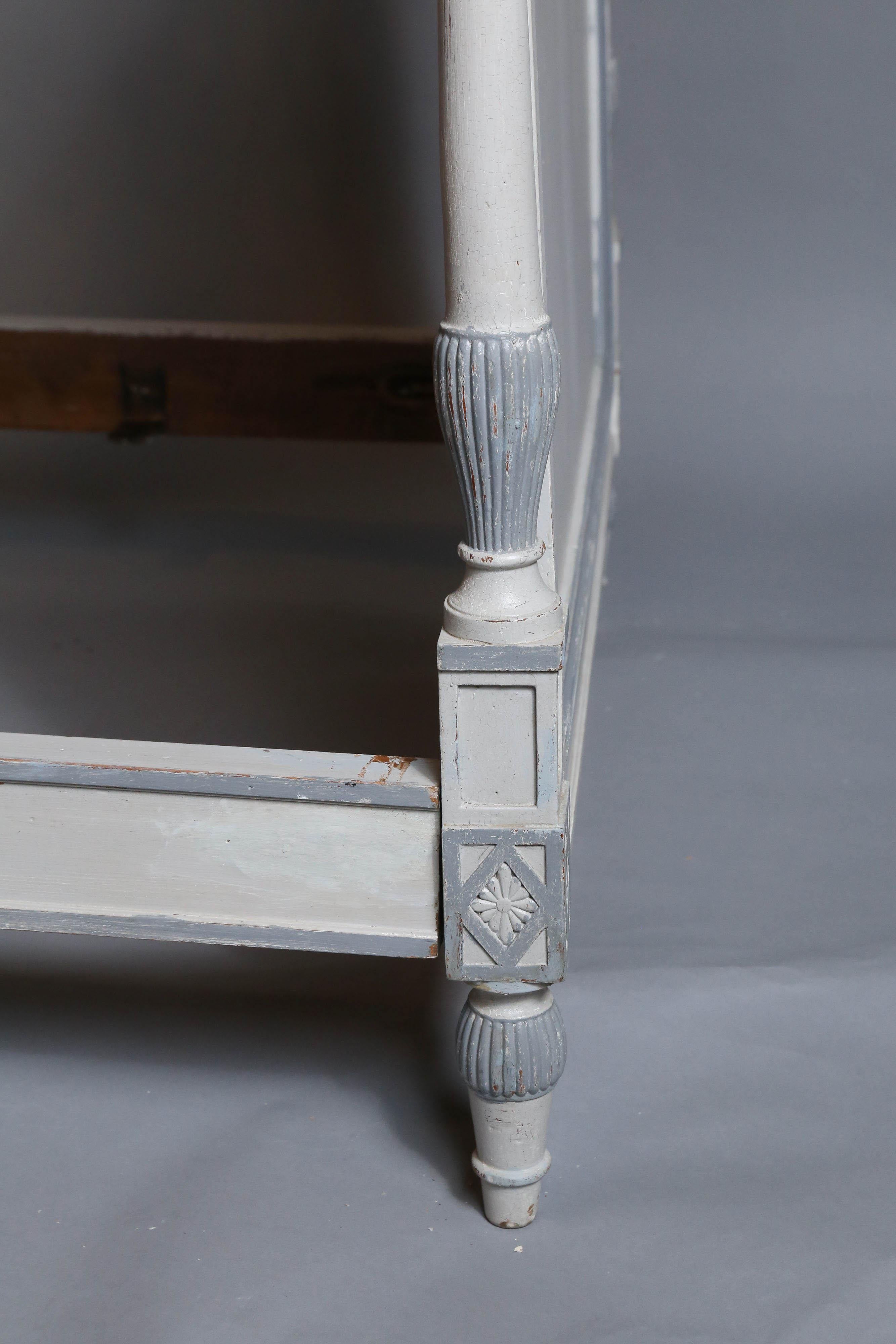 Classical Directoire daybed with fluted pilaster and rosette carvings, painted in light grey with darker grey accents.