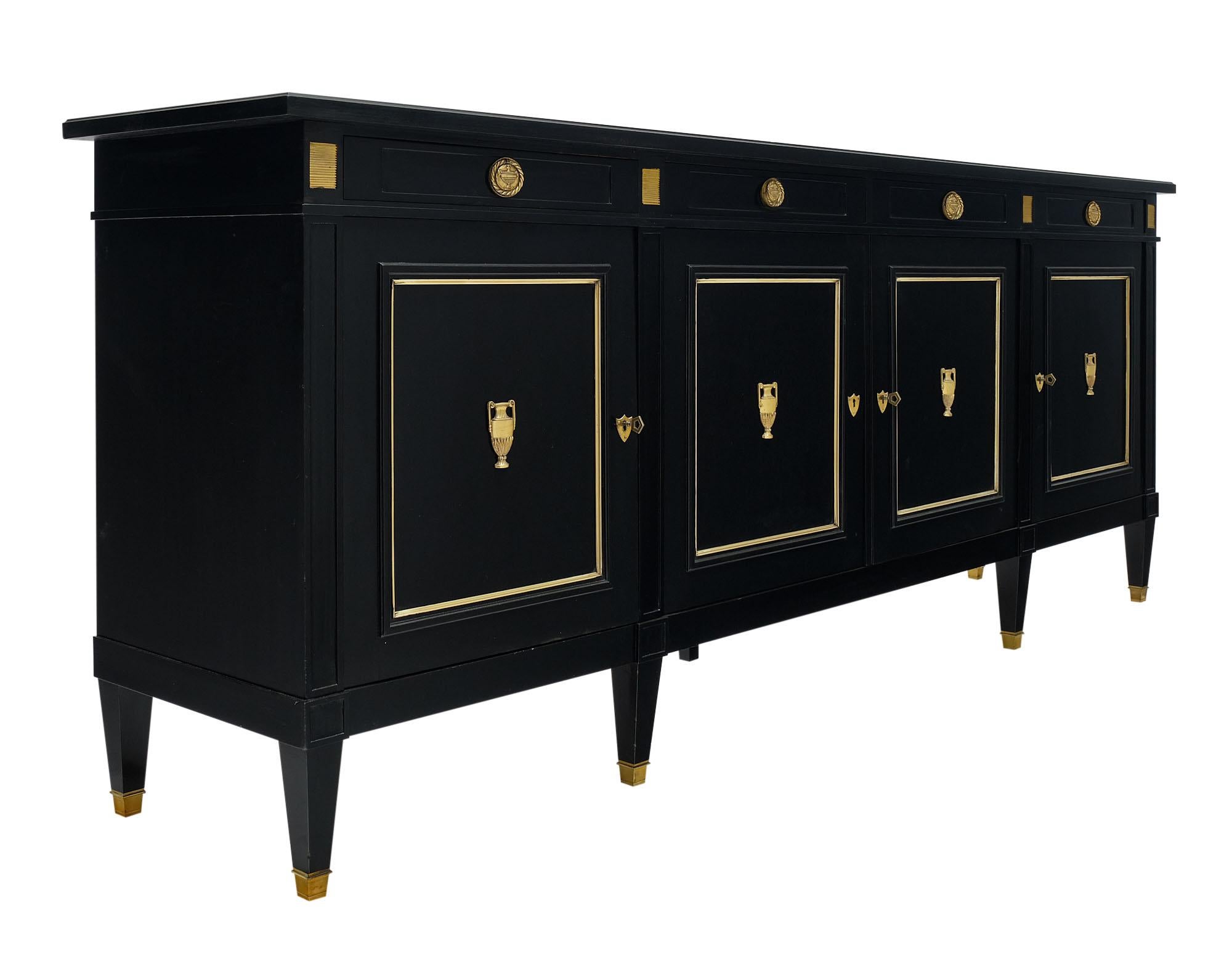 Buffet / enfilade from France made of solid mahogany that has been ebonized and finished with a high luster French polish. There are gilt brass trims throughout and finely cast brass urns “à l’Antique” on all four doors with working locks and keys.