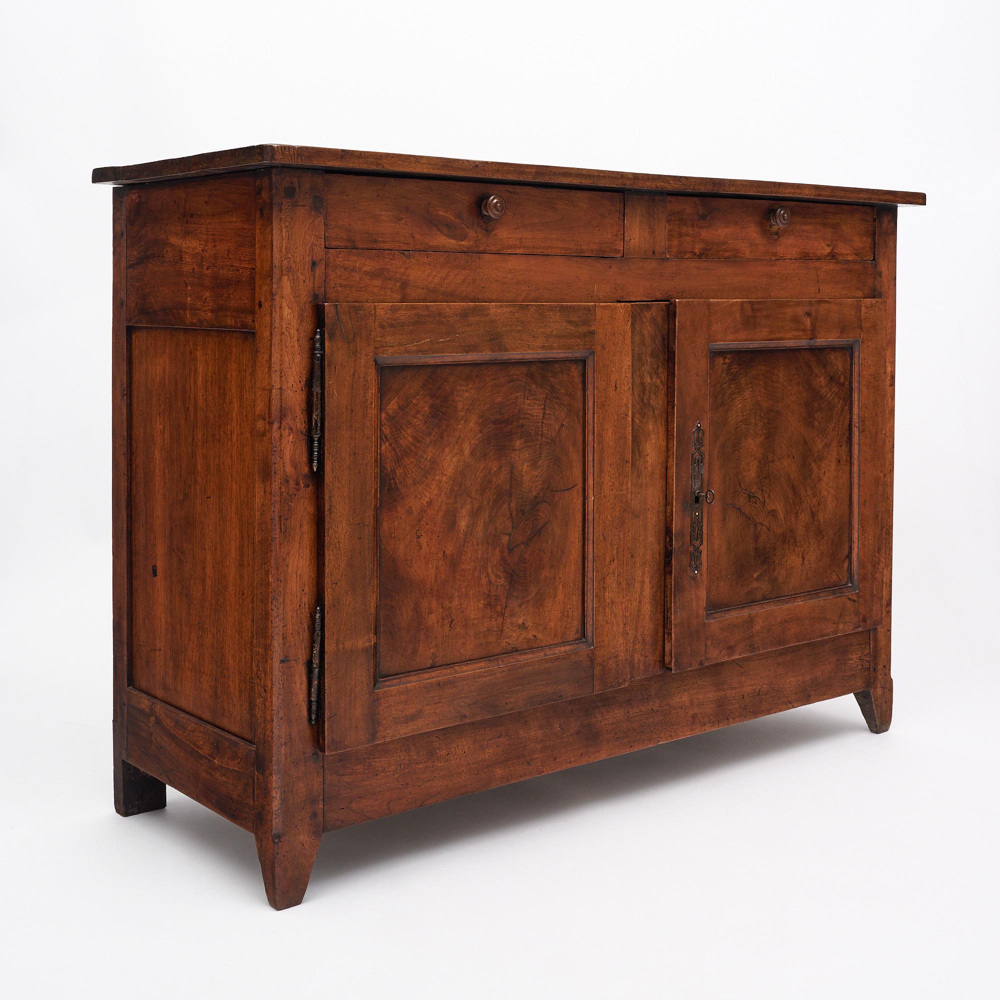 Buffet français de l'époque du Directoire. Cette pièce est fabriquée en bois massif, principalement en noyer. La partie supérieure comporte deux tiroirs à queue d'aronde avec des poignées en bois. En dessous, deux portes s'ouvrent sur des rayonnages