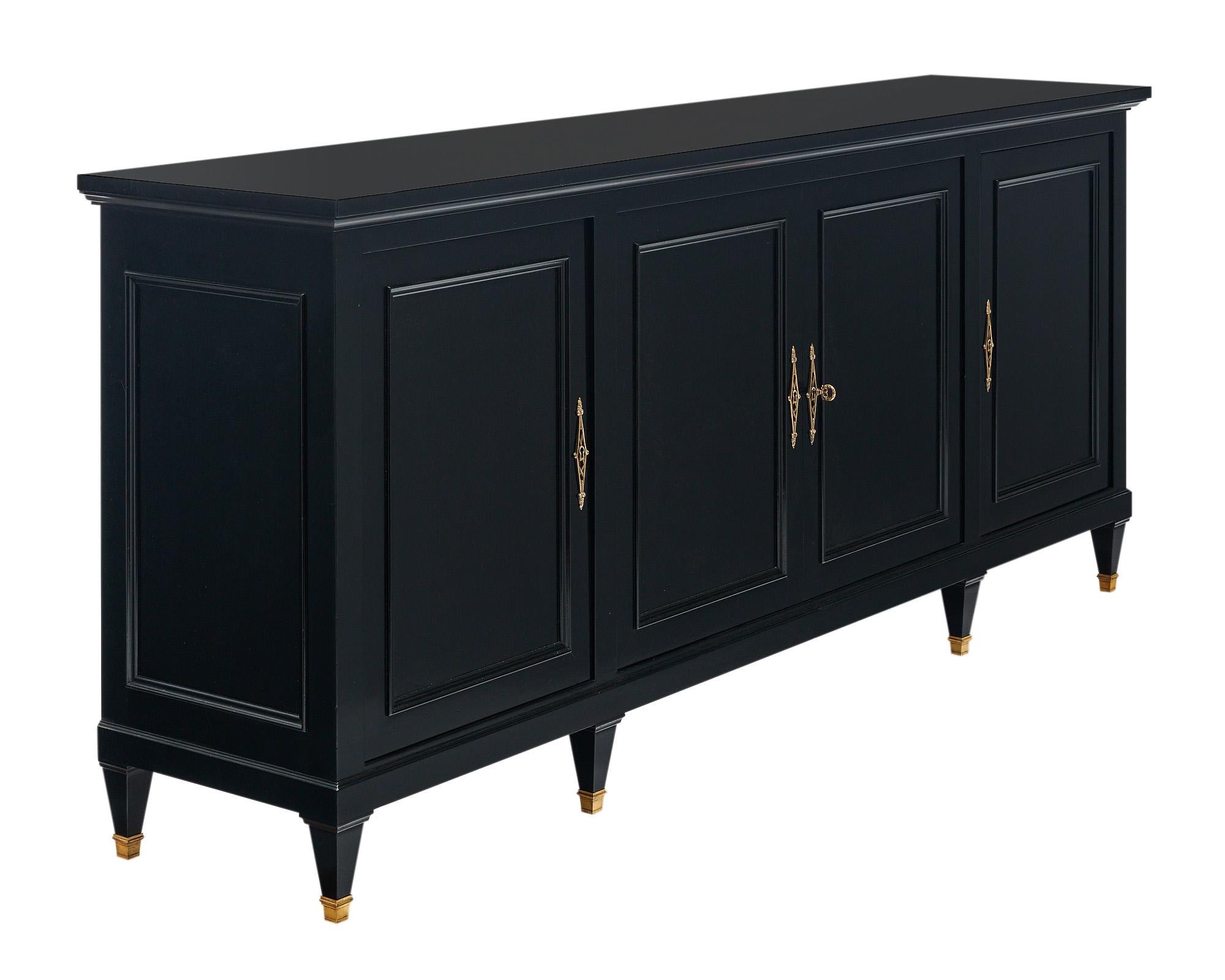 Buffet from France in the Directoire style. This piece is circa 1910. It is made of solid wood construction, primarily cherry-wood. There are four doors that feature detailed brass hardware. The locks are in working condition and there is one key.