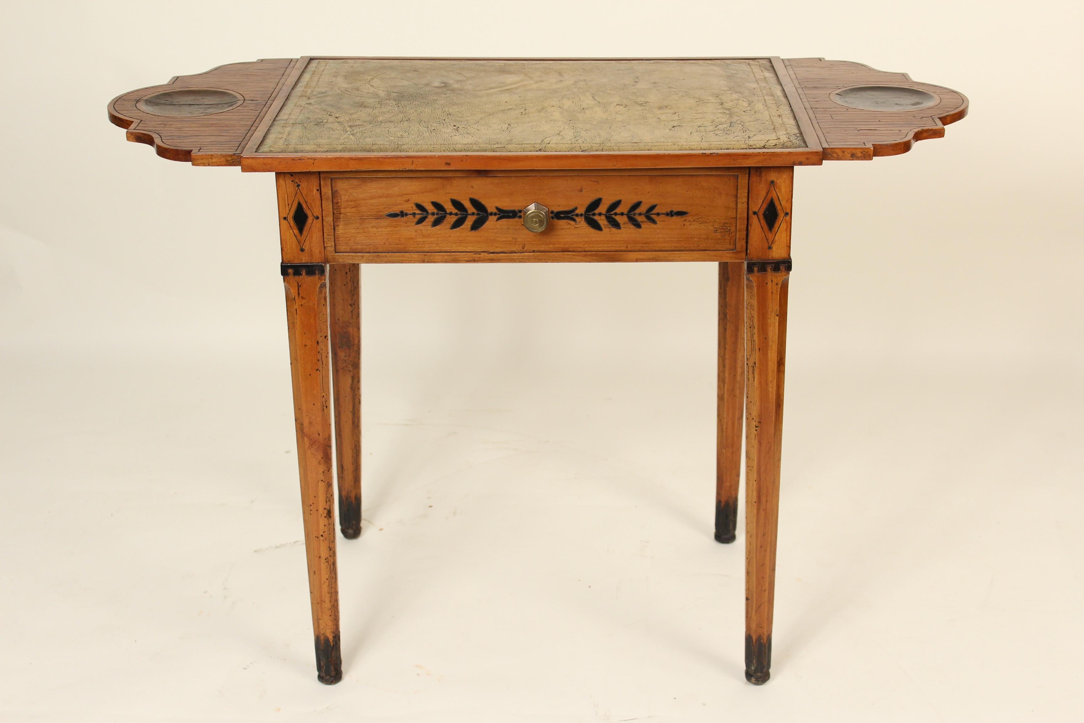 Directoire fruit wood writing table, with engraved and ebonized decorations and a tooled leather top, circa 1800. The top is stationary, the ends do not fold down.