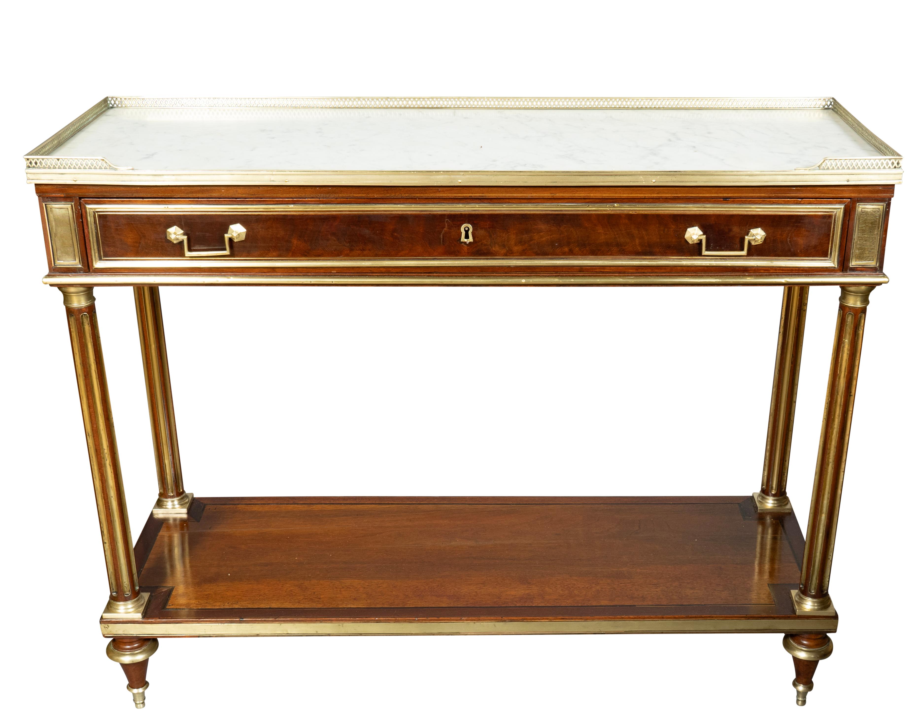 Rectangular inset white and gray marble top with brass 3/4 gallery over a frieze drawer with square bail handles. Brass inlaid reeded circular legs joining a lower shelf. Toupie feet.