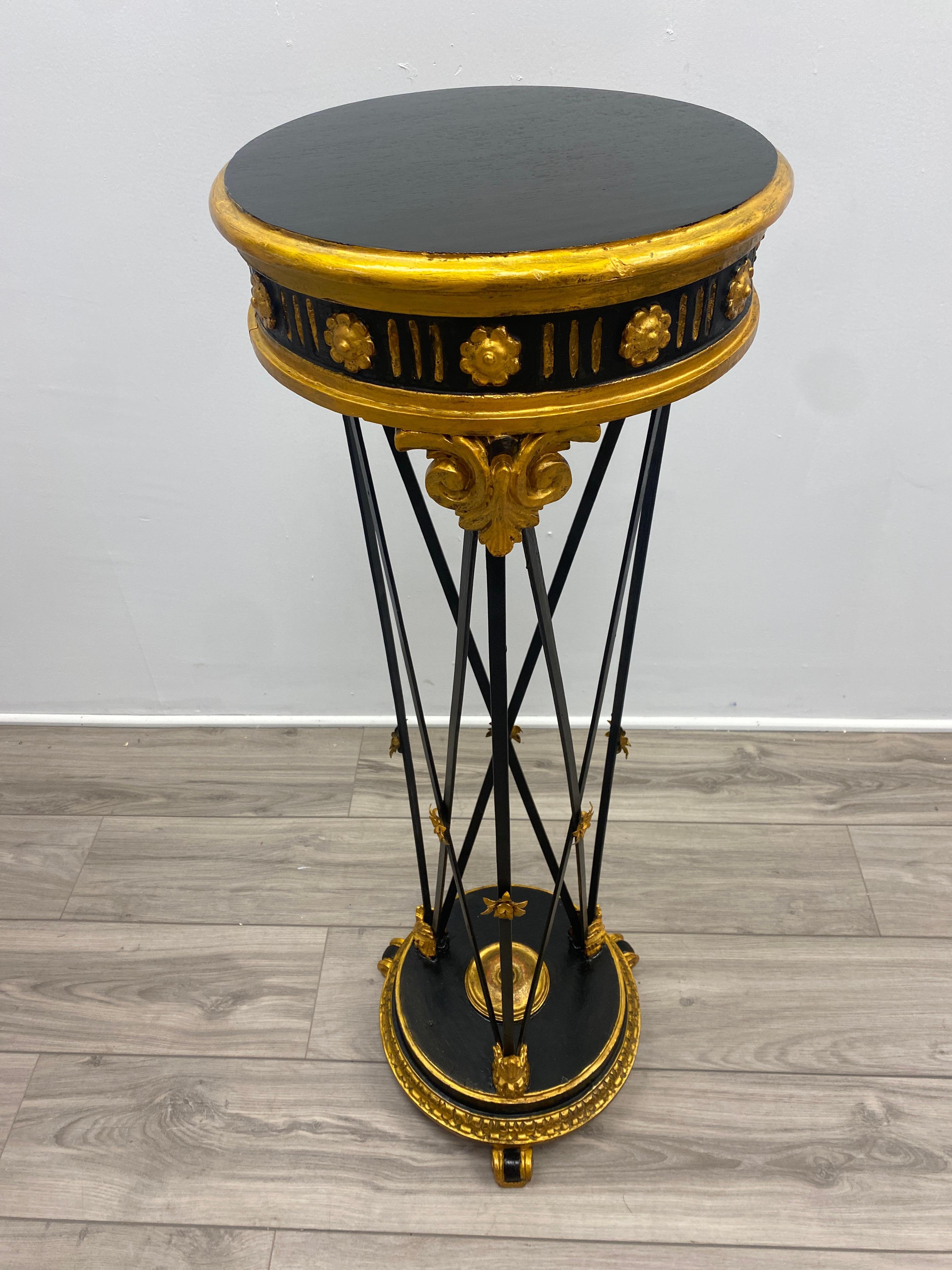 Handsome directoire/neoclassical style plant stand from the early 20th century. Ebonized Mahogany wood surfaced. Fluted apron adorned with giltwood medallions, flutting, and Carved Acanthus details. Wrought iron crossing uprights support with an