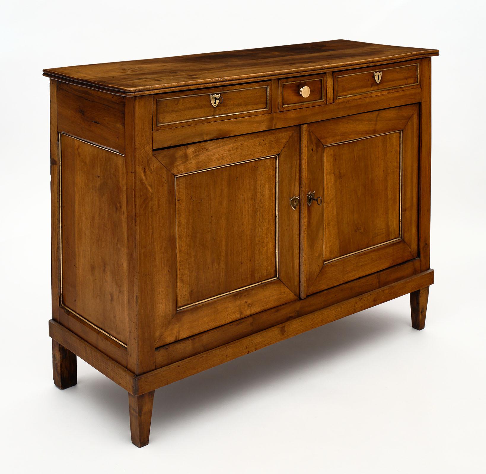 Directoire period antique French buffet made of solid walnut and featuring three dovetailed drawers above two doors. The doors open to reveal interior shelving. We love the tapered legs and clean lines of this classic piece. The doors and sides are