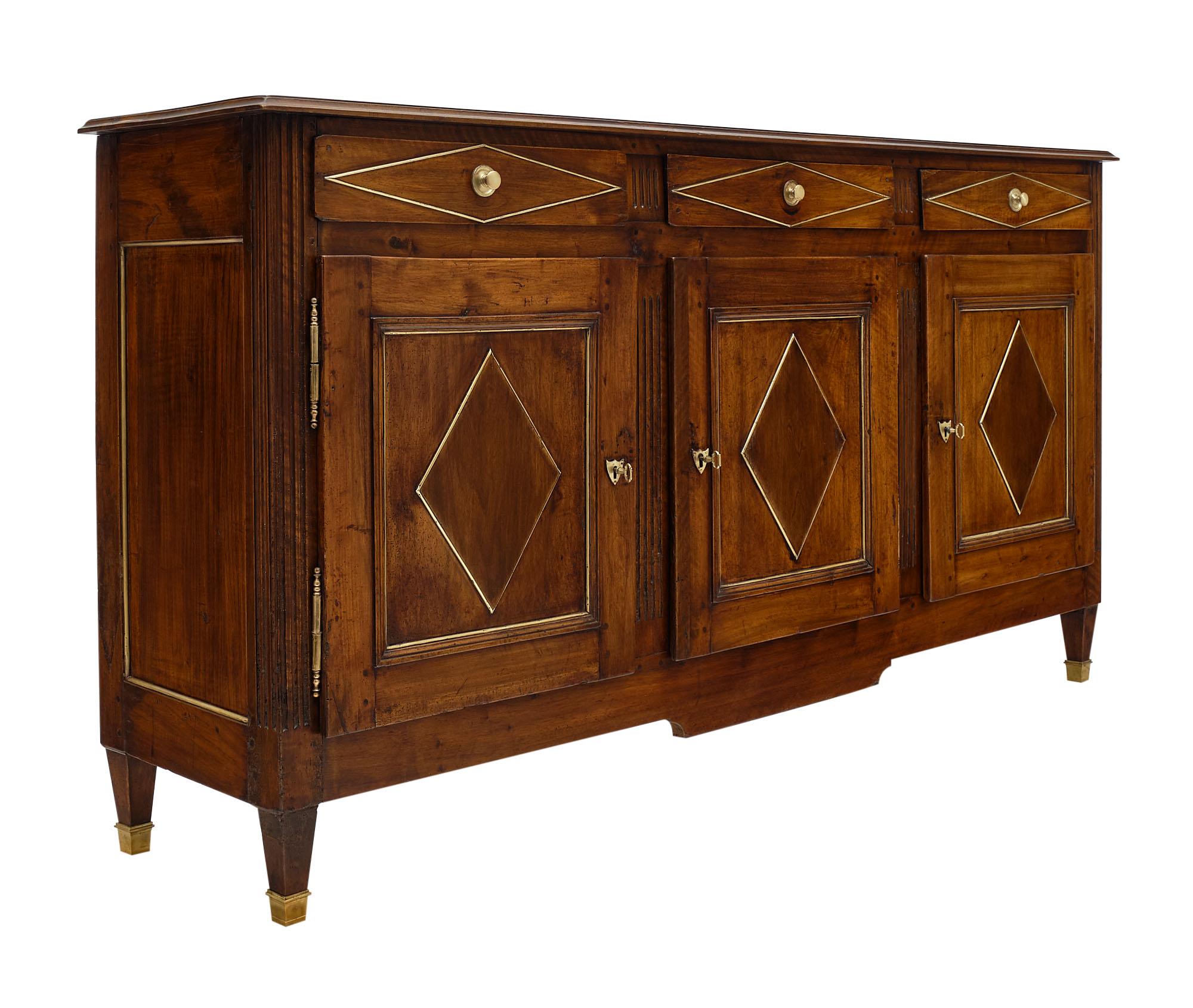 Buffet from the Directoire period in France. This piece is made of solid walnut from the Rhone Valley. There are three dovetailed drawers above three doors adorned with a hand-carved motif in high relief and gilt brass trims throughout. Square
