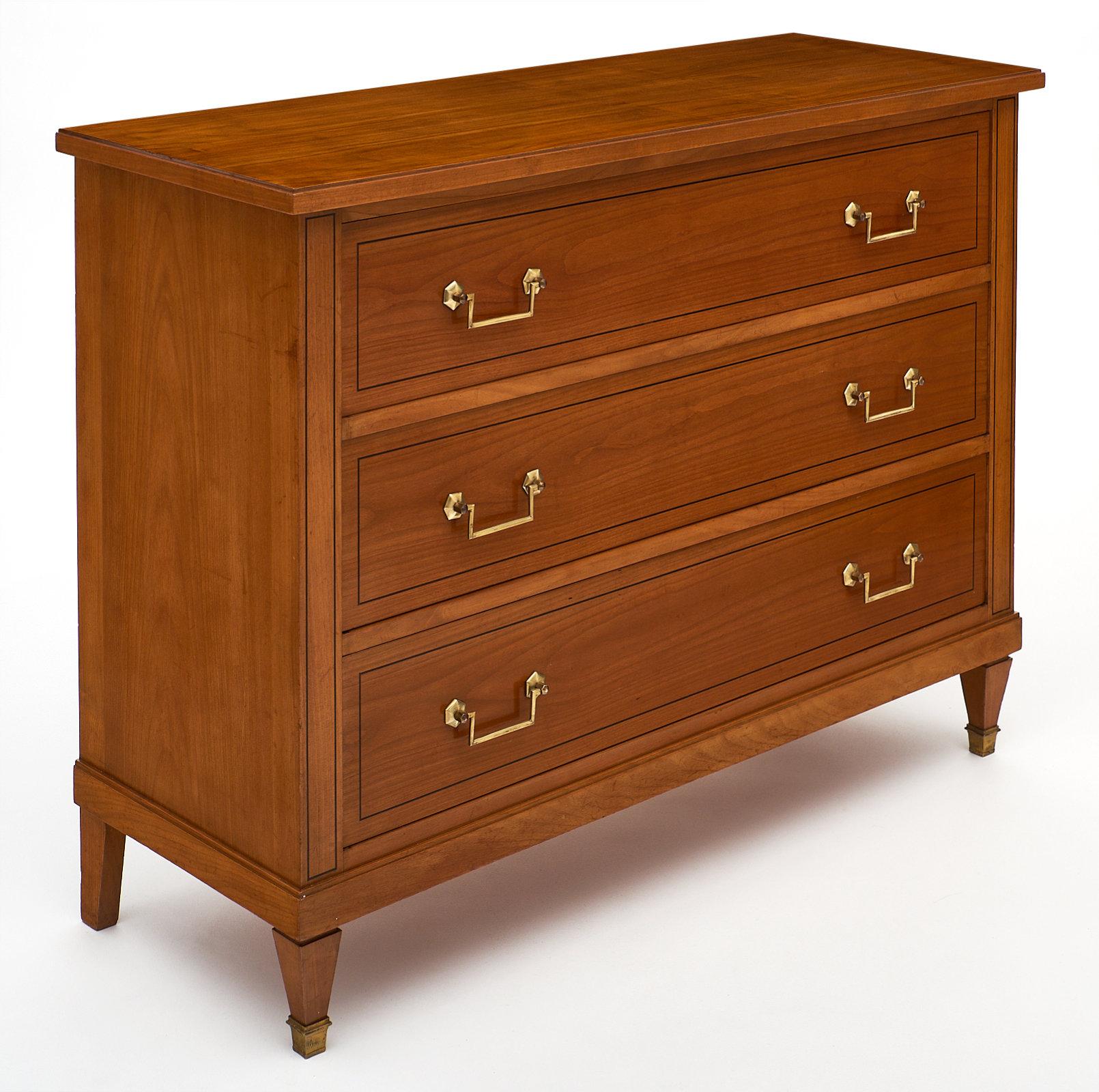 French Directoire style chest of drawers made of cherry wood with three dovetailed drawers and gilt bronze handles and feet. We liked the clean lines, understated feel, and the fine craftsmanship in the ebony inlay details.
