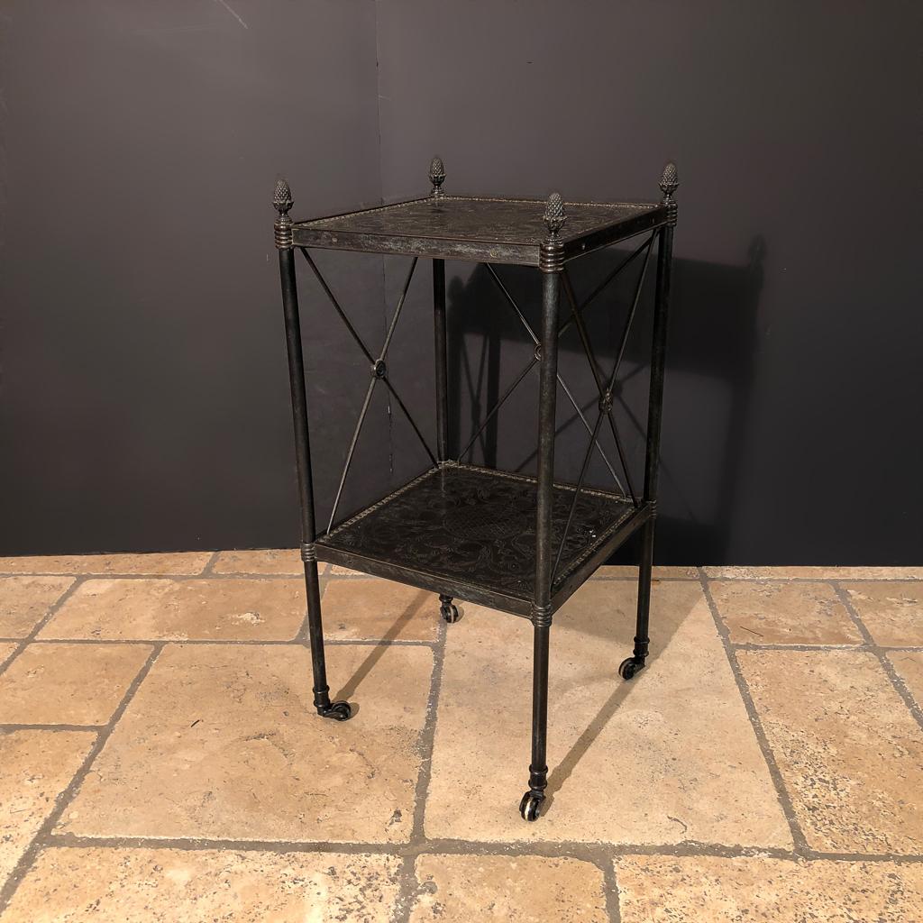 A French Directoire style bronze two-tier low side table with etched brass decoration to the top and lower shelf, with acorn finials and brass caster feet.
