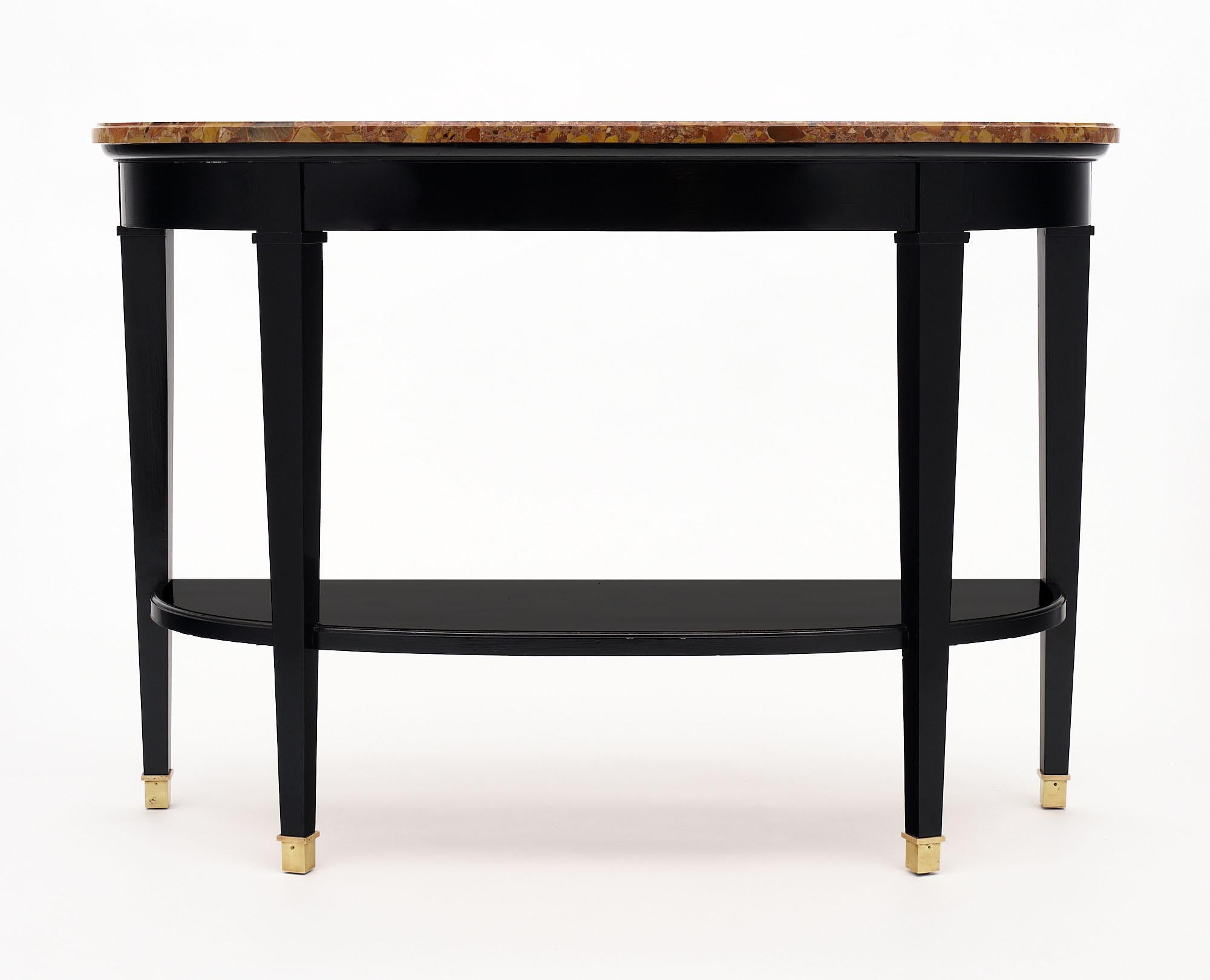 Pair of consoles from France in the Directoire style. Each is topped with a “Brêche Royal” marble top; intact and original. Each table features four square tapered legs with a bottom shelf of ebonized cherry wood finished in a lustrous