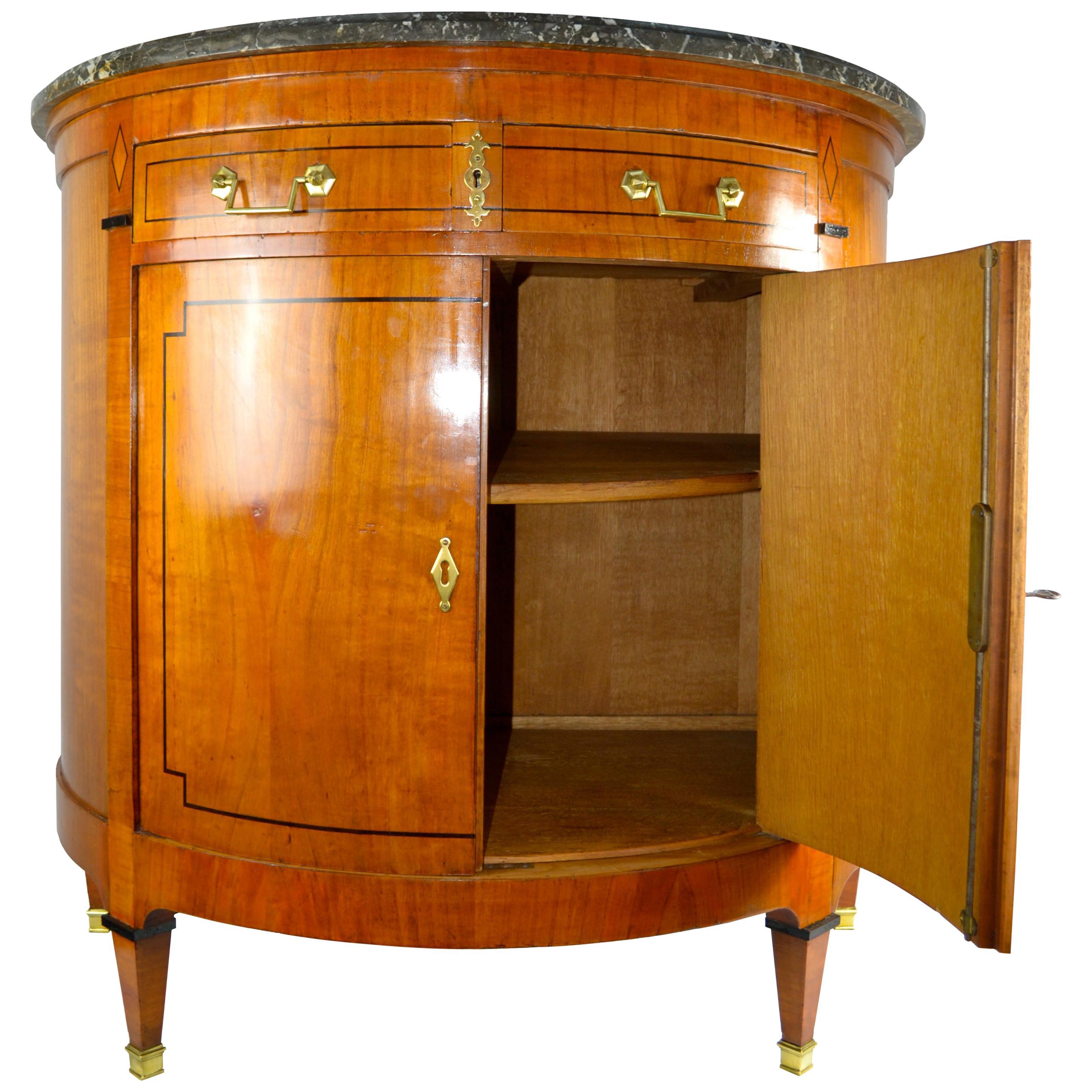 A simple classically inspired Directoire style demilune commode (1790-1805). The cabinet has a shaped grey mottled marble top over two top drawers and two main doors. The fruitwood carcass is inlaid with ebony banding. Were common.