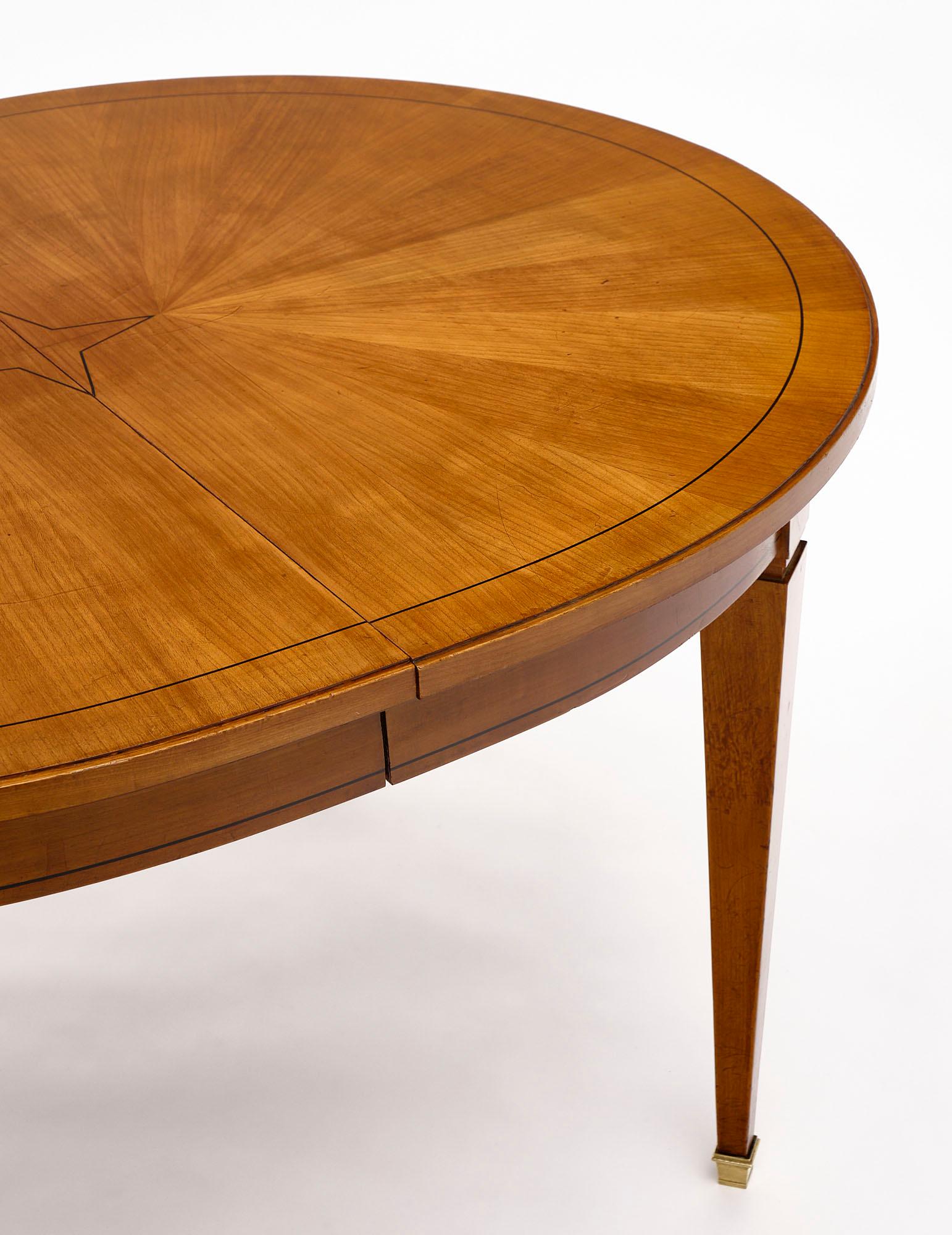 Directoire style dining table from France made of solid cherrywood and featuring a sun marquetry with ebony inlays. There are two solid cherrywood leaves as well; each adding 19.625” to the total length. The feet are capped with brass.