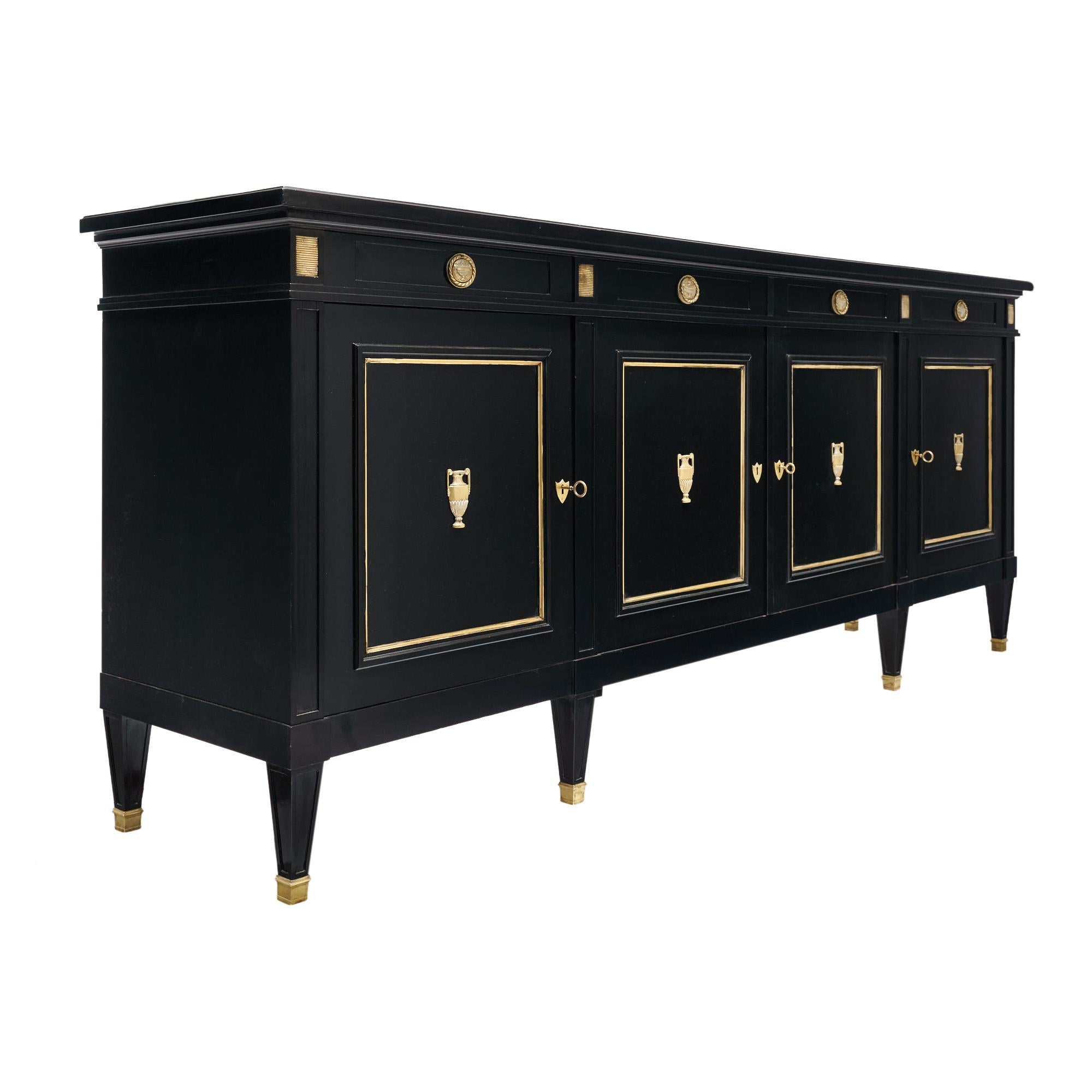This impressive French antique grand buffet crafted in the Directoire style is made of solid wood construction, primarily mahogany. It showcases a magnificent neoclassical design with four dovetailed drawers and four doors revealing adjustable