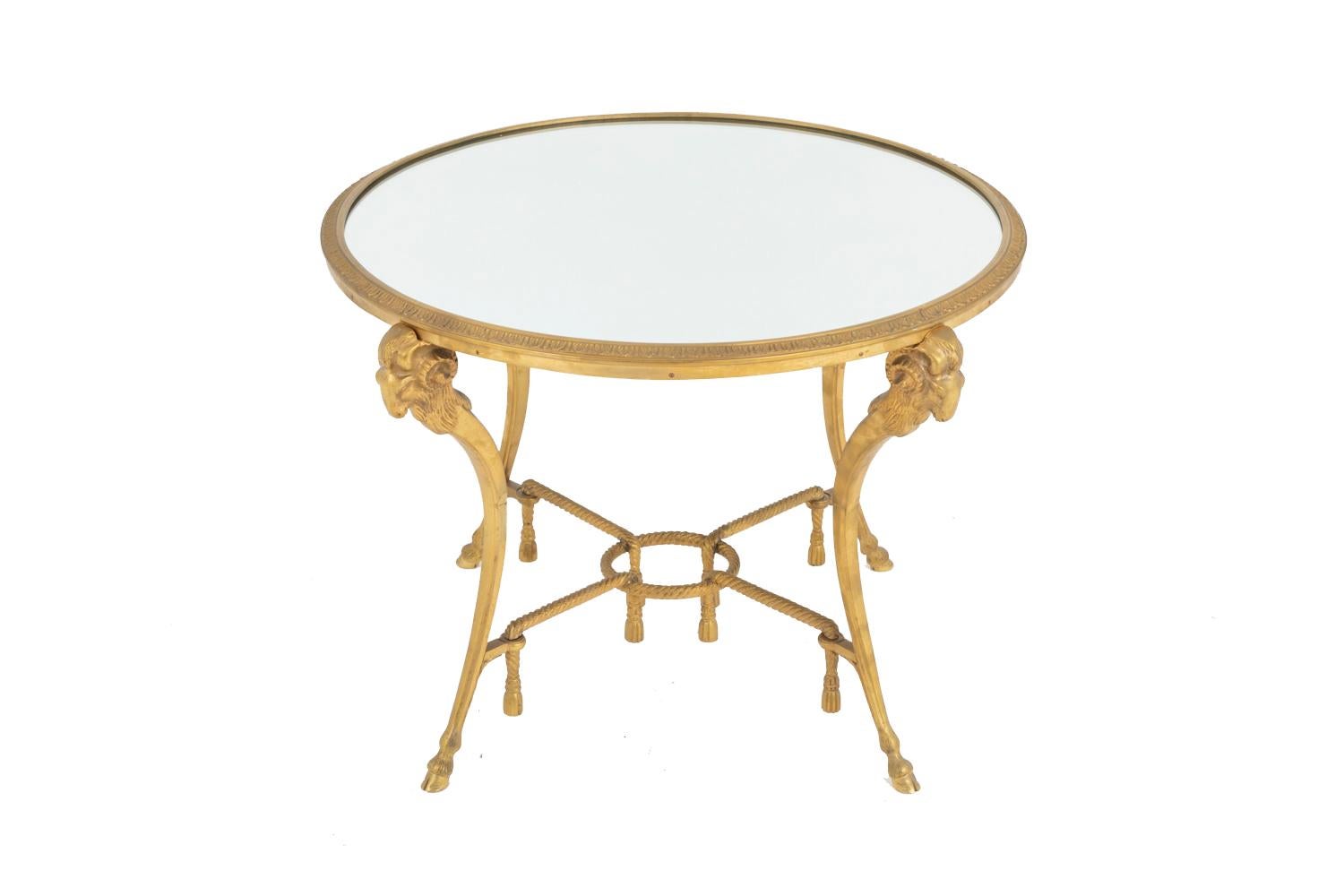 Directoire style round end table in chiseled and gilt bronze. It stands on four saber legs ending in hoof feet et adorned with a ram head on the upper part. Legs are joined by an X-shaped stretcher imitating twisted rope and decorated with acorns.