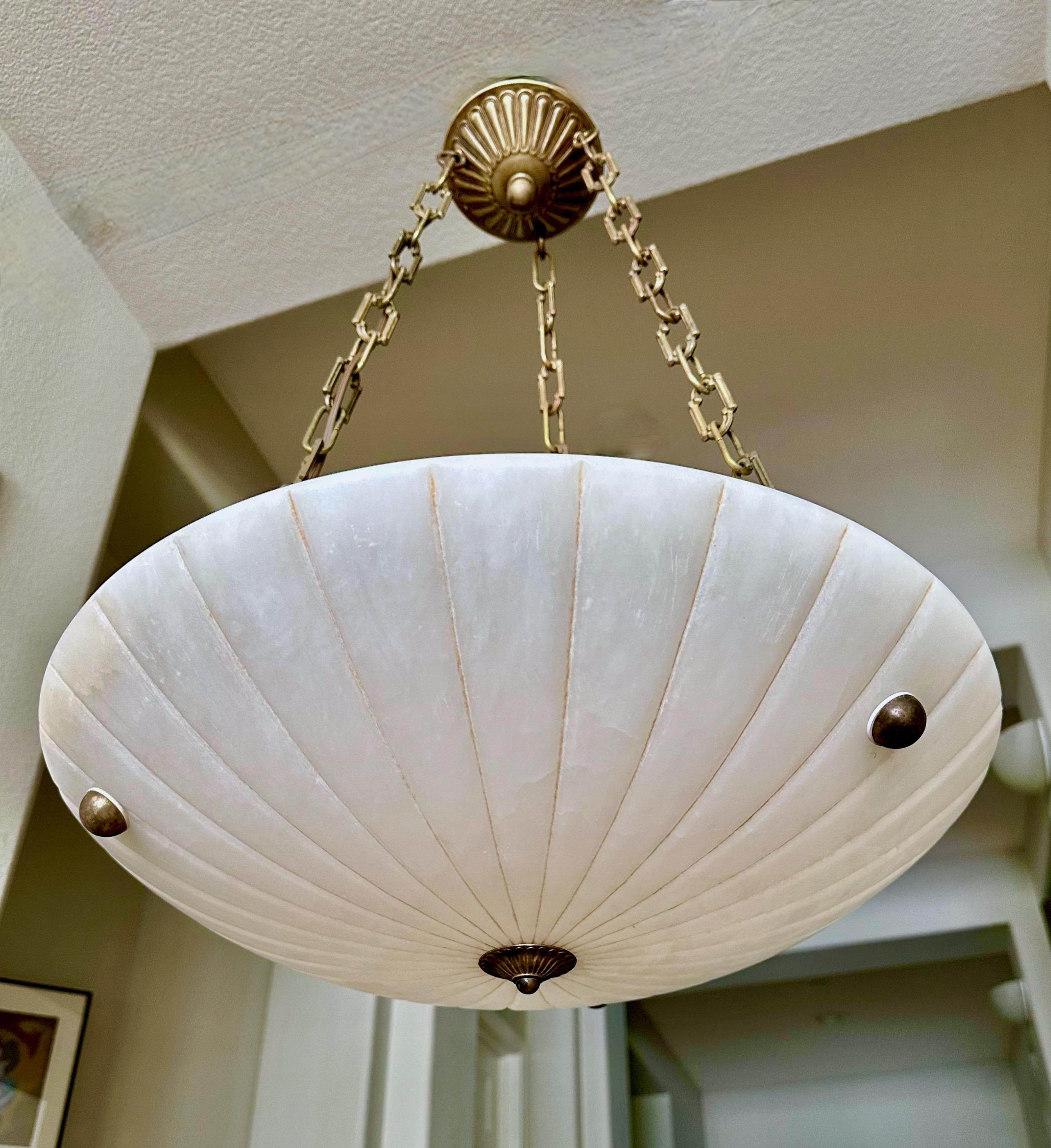Lampada a sospensione in alabastro francese con finiture in ottone invecchiato (anticato) in stile Directoire. L'illuminazione interna utilizza 3 lampadine normali da 60 watt con base A (si consigliano i led). Cablata di recente. 
