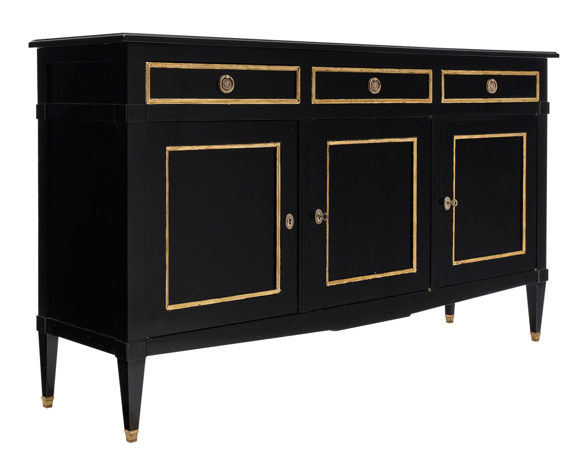 Directoire style French antique ebonized buffet with three dovetailed drawers above three doors featuring adjustable shelving within. Finely cast bronze hardware is accented with gold leaf trim. This piece has been finished with an ebonized French