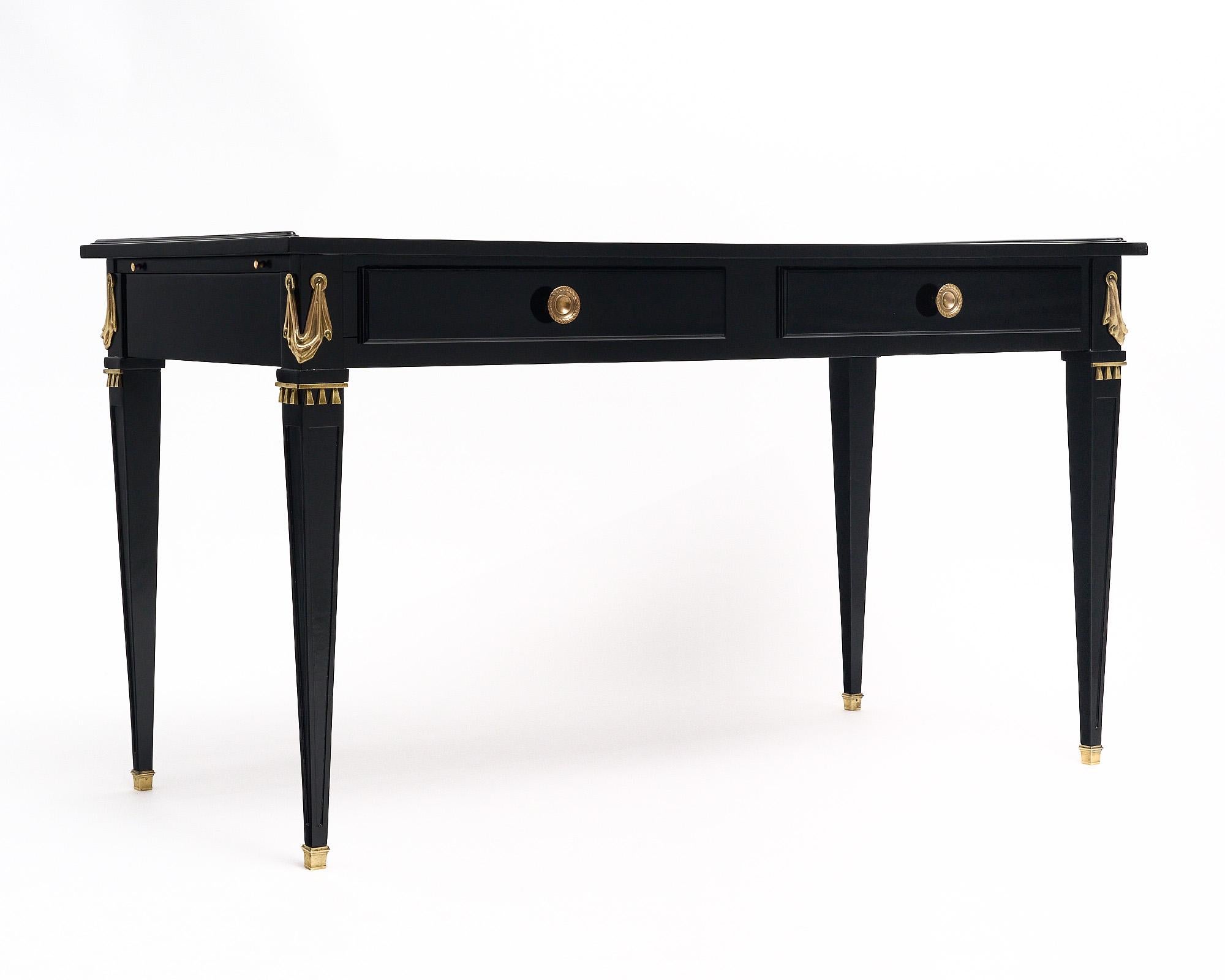 Writing desk from the Art Deco period in France and in the Empire style. This piece is finished with an ebonized museum-quality French polish. The top is covered in an original tan leather writing surface with a gold-leafed embossed trim. The desk