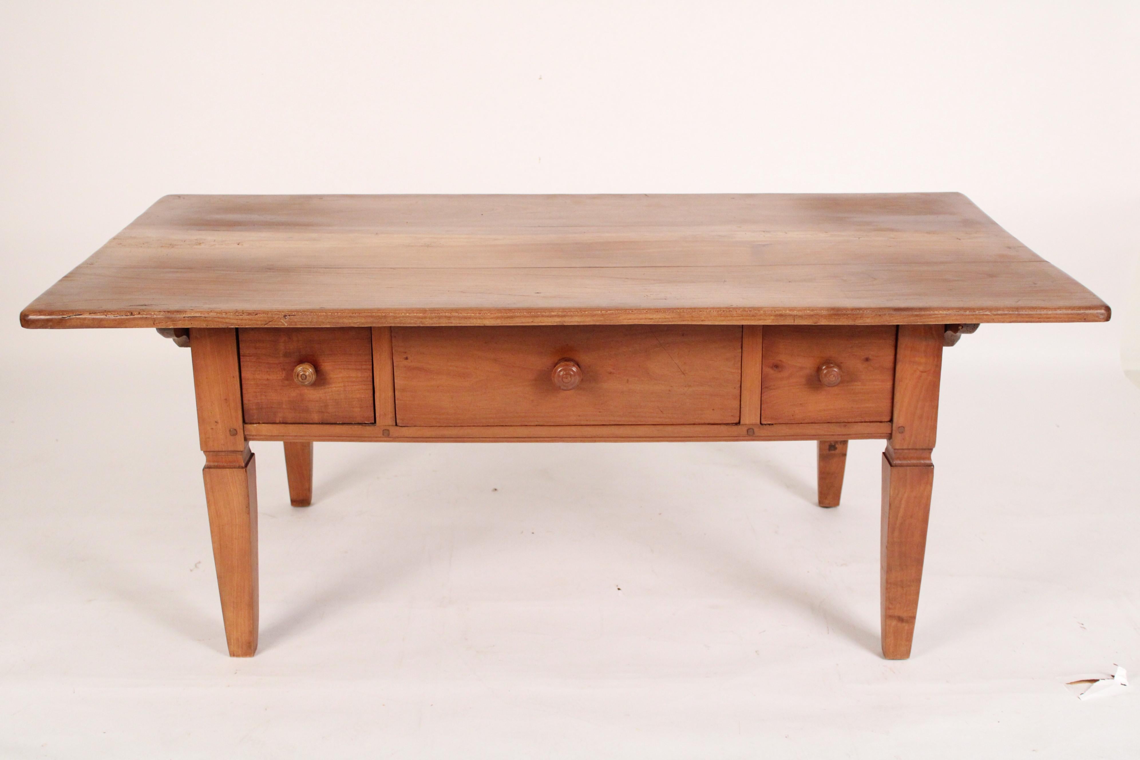 Antique Directoire style fruit wood coffee table, 19th century. With an overhanging 3 board top, 3 frieze drawers with wood knobs, resting on square tapered legs. Mortise, tenon and peg frame construction and hand dovetailed drawer construction.