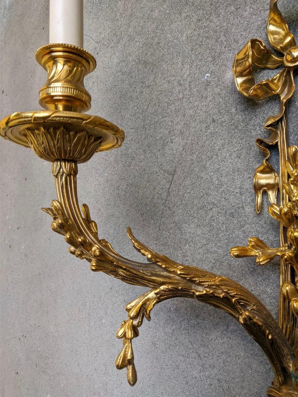 This French Directoire style sconce features top-quality chiselled bronze, with many vivid details typical of the end of the 18th century. At the top, there is a staple, a typical element of the Louis XVI period. Below this, there is a bunch of