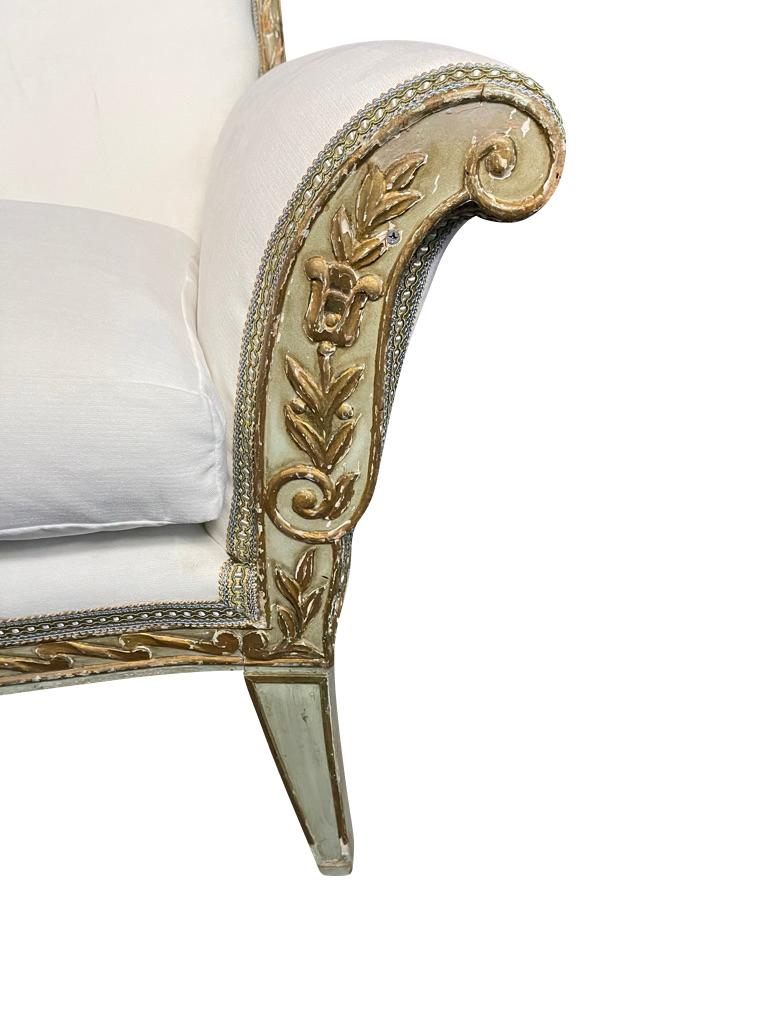 Directoire style green and gilt painted parcel-gilt sofa with elegantly curved back ending in flared corners. Sabre legs and exquisite carving and parcel-gilt throughout. Flared arms ending in scrolled ends with exquisite parcel-gilt foliate and