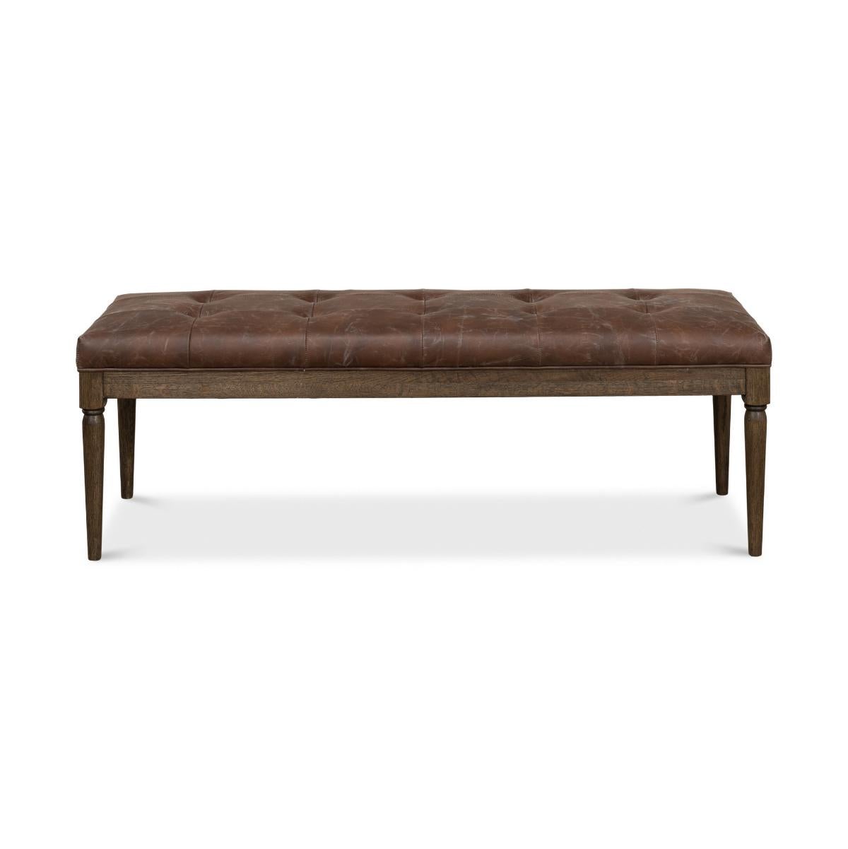 A French Directoire style leather bench with a button tufted antique brown leather on an oak base with a warm finish and turned and tapered legs.

Dimension: 51