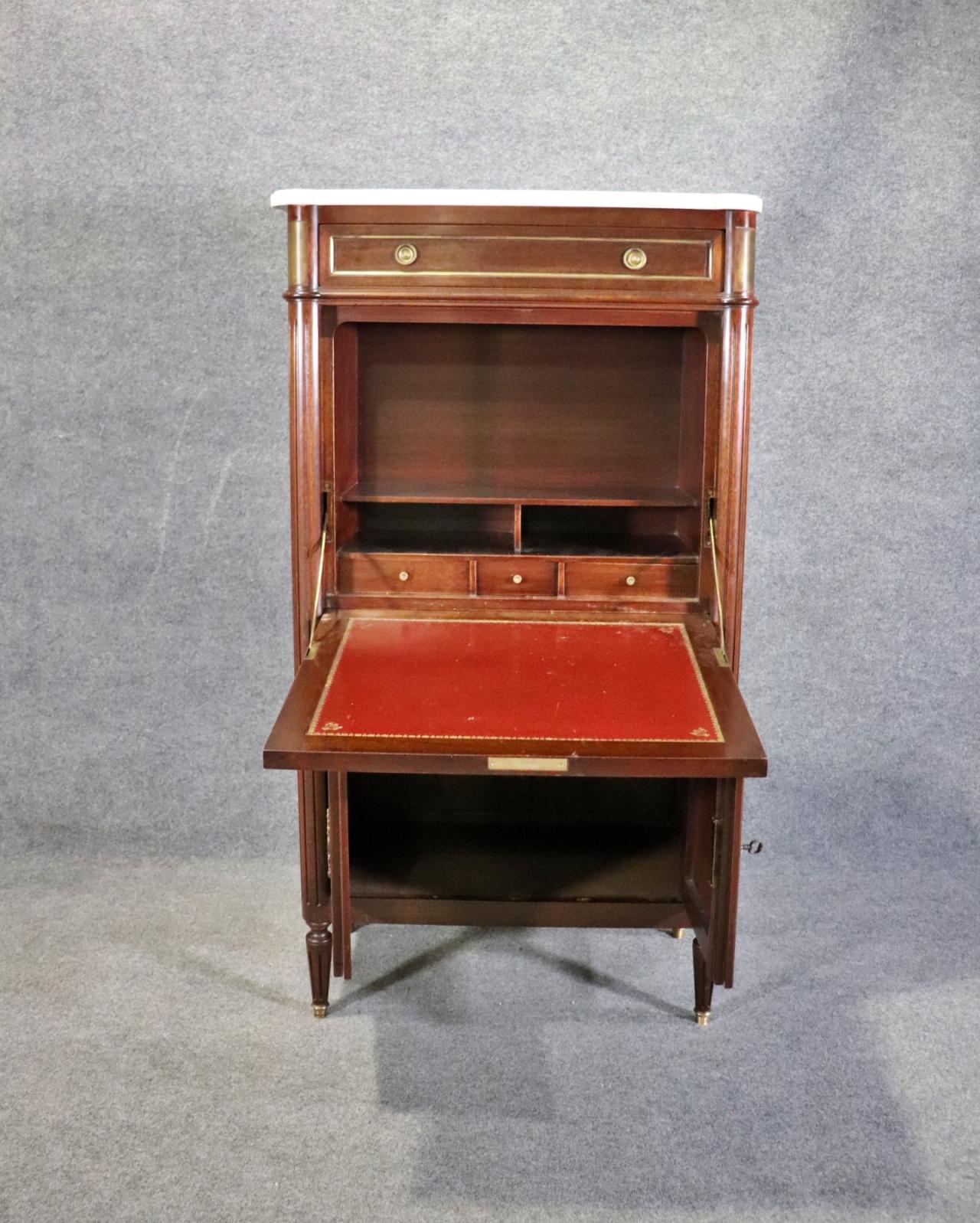 Marble top. One dovetailed drawer on top. One drop down door containing  leather and fitted interior. Two doors on bottom containing one shelf. Brass or bronze hardware and accents. Gilt accents.  57 1/8