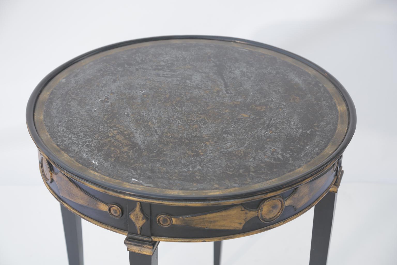 Occasional table, in Directoire taste, having around églomisé top with mottled decoration, on a base of black lacquer, its apron outcarved with gilt strap decorations, raised on square-section tapering legs.

Stock ID: D2807.