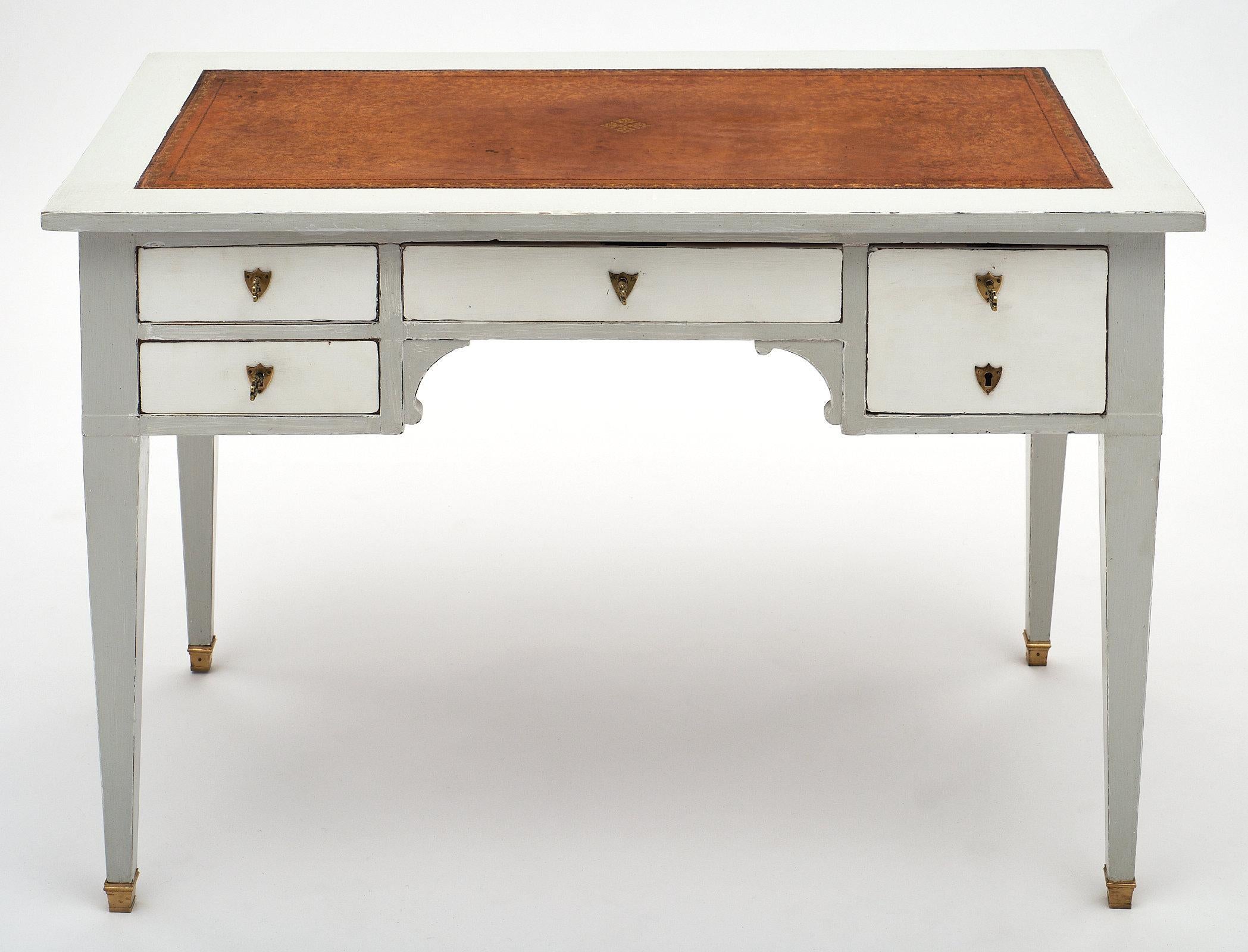 Painted Directoire style desk with leather top. This piece is made of solid mahogany and hand-painted in white and trianon grey. There are five dovetailed drawers, and the back features hardware, making it a faux partner desk. We love the beautiful