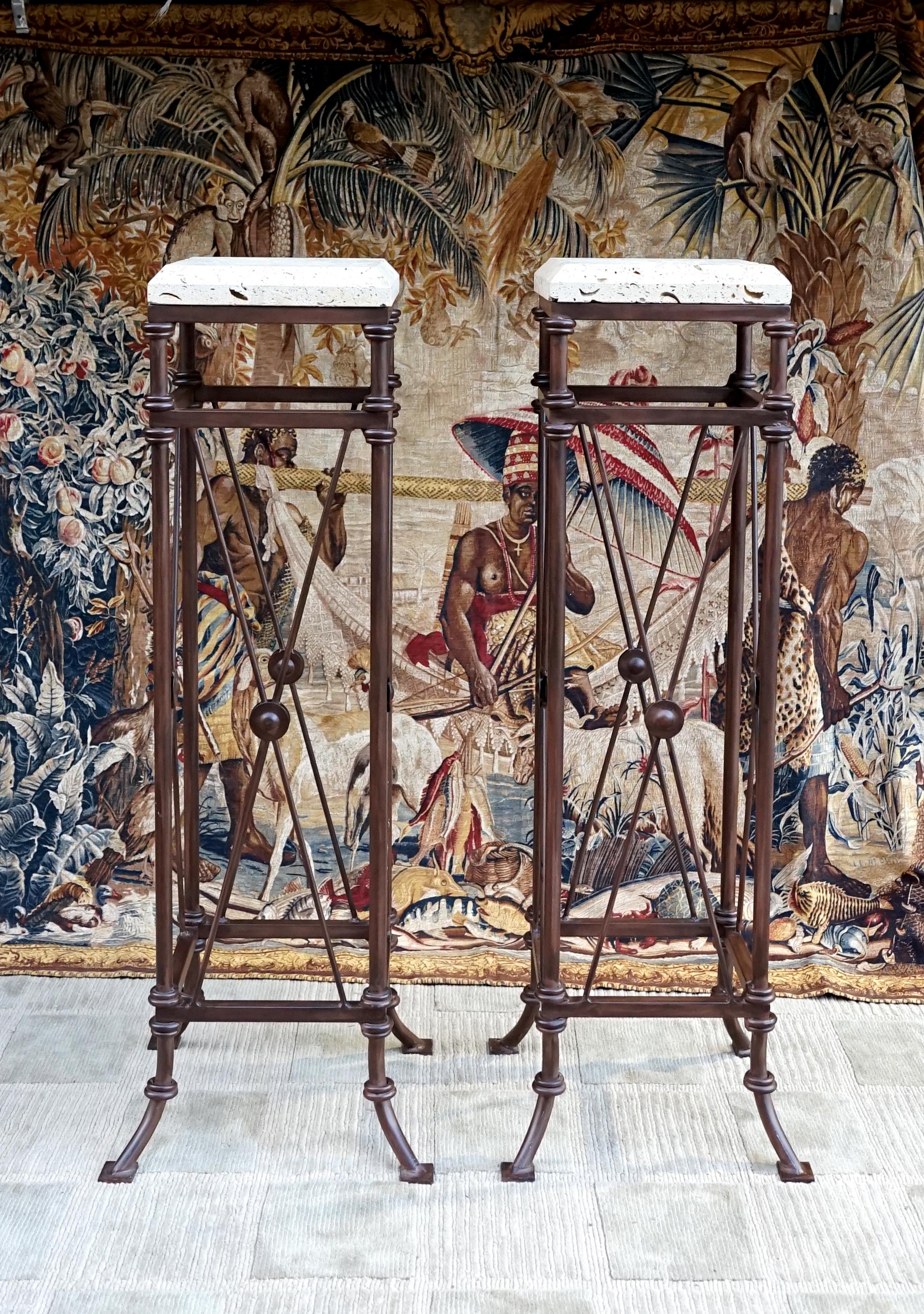 A pair of Directoire style wrought iron plant or candle stands offer lots of decorating options in a foyer or entryway, at the foot of a stairway or in a garden space. The stands are almost a perfect square with off white Travertine top shelves,