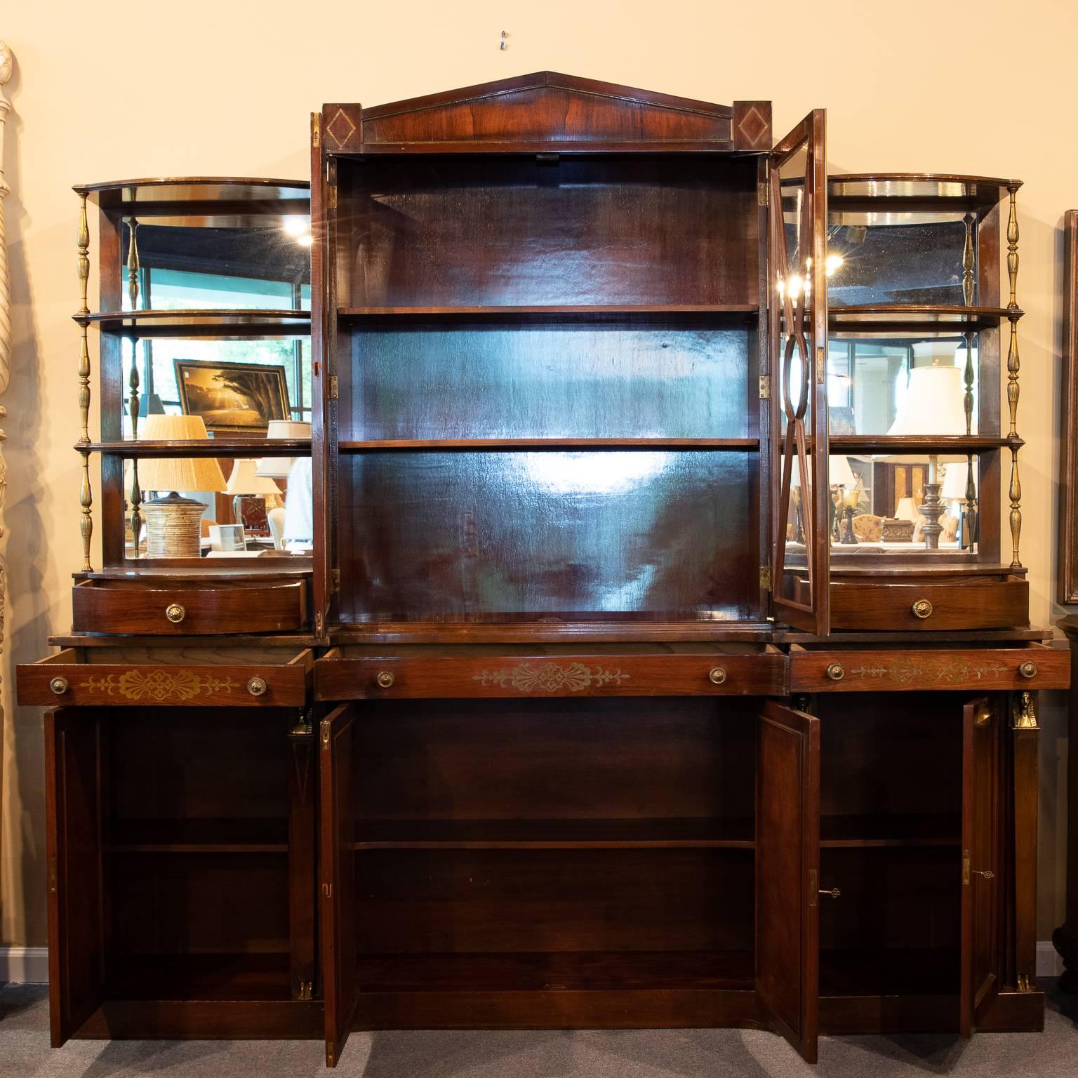 Directoire style rosewood display cabinet with brass inlay. The top is centred with two doors each with bubble glass, interesting sash design of five pieces of glass and centre round piece. Lanking the sides of the cabinet are mirror back etergere