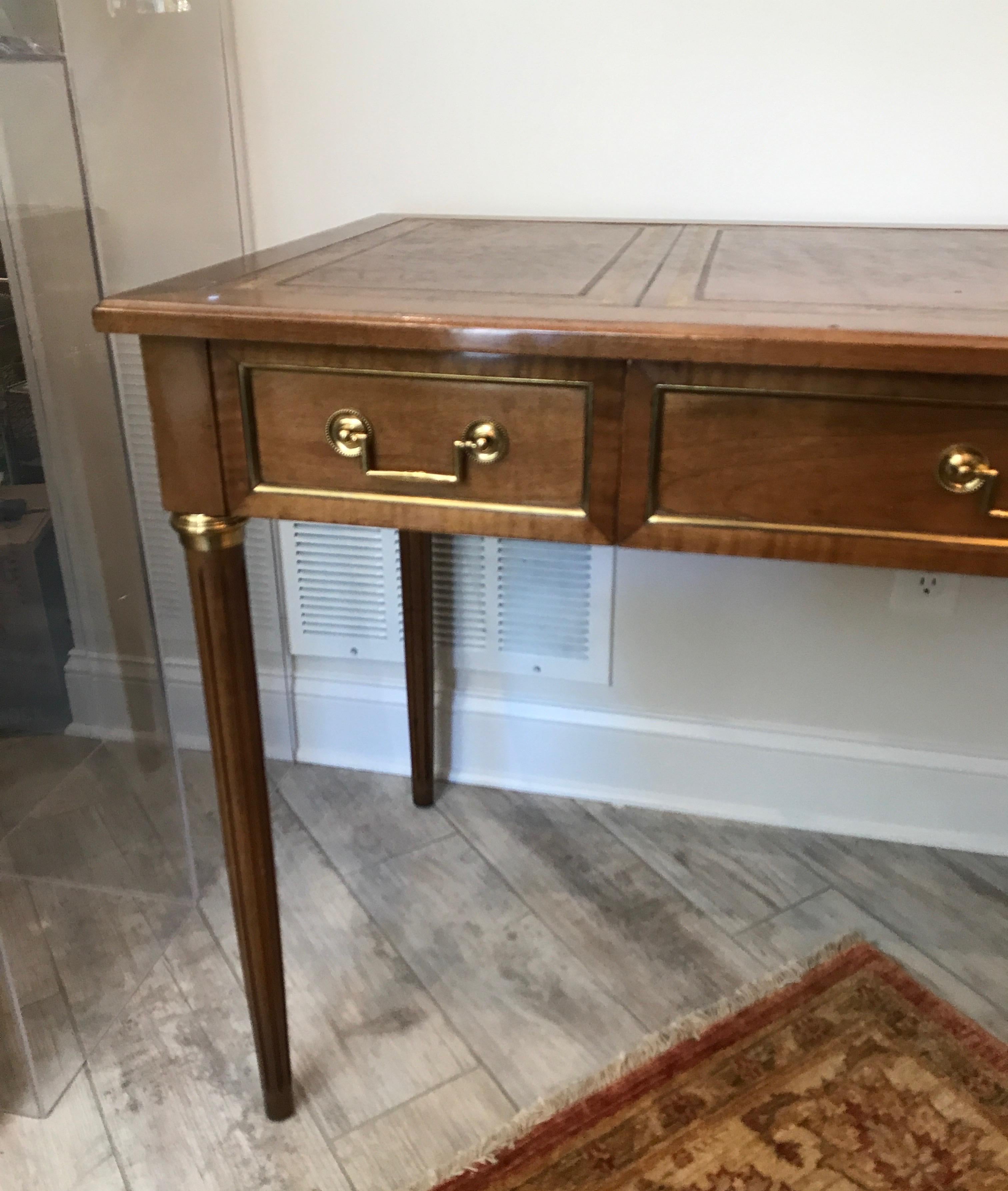 Directoire style three-drawer desk with tooled leather writing surface and brass inlay's.