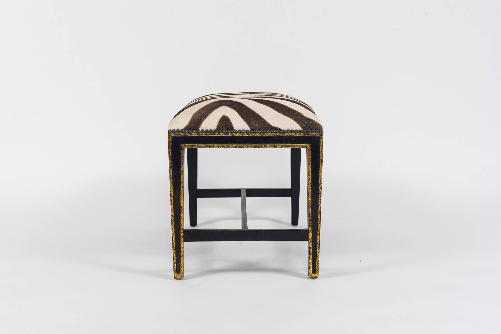 A 20th century gilt and ebonized Directoire style zebra printed hair hide bench.