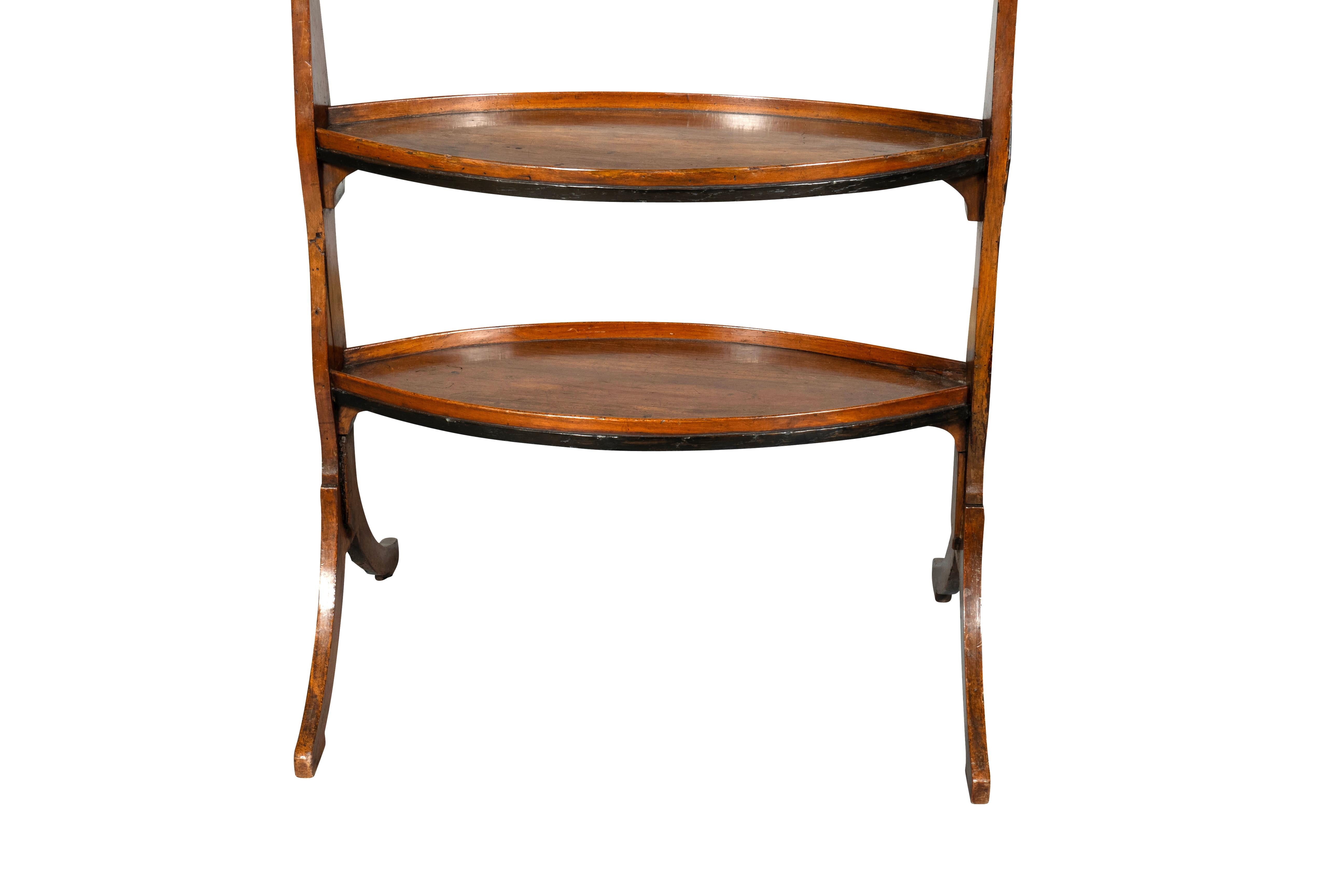 Elongated octagonal top with gallery and fold down hinged panel. Trestle base with two oval lower shelves. The trestle sides with ebonized lozenge decoration. These tables were made originally as work or sewing tables.