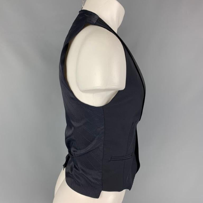 DIRK BIKKEMBERGS u-neck style four buttons vest comes in a black and navy polyester blend material featuring a shawl collar, welt pockets, back belts, and a buttoned closure. Made in Italy. Excellent Pre-Owned Condition. 

Marked:   L