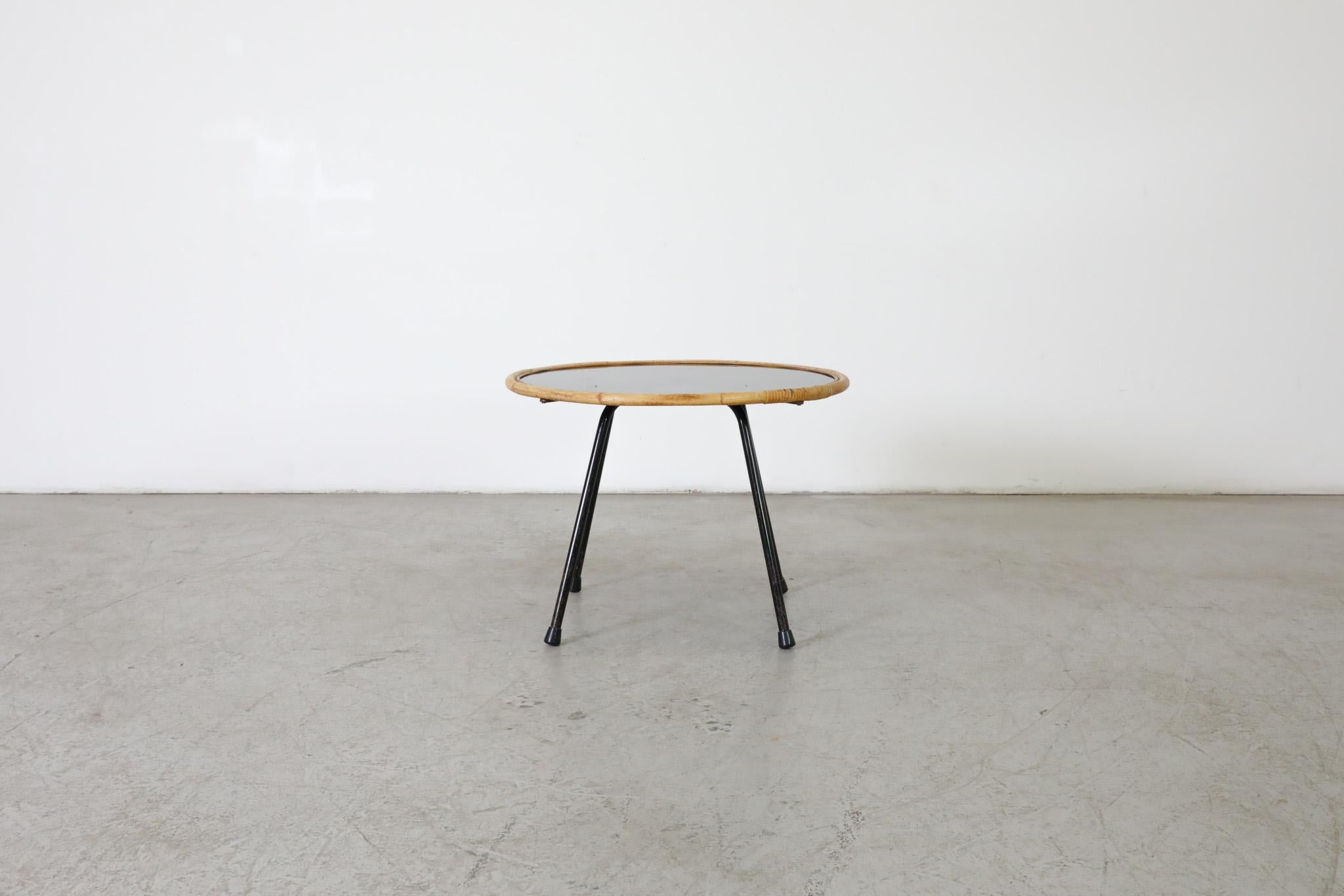 Attractive Mid-Century side table with a unique combination of a black glass top, black enameled metal frame and hand-woven bamboo rim. Stylish and sleek light weight side table Attributed to Dutch Mid-Century designer Dirk van Sliedregt, 1960s. A