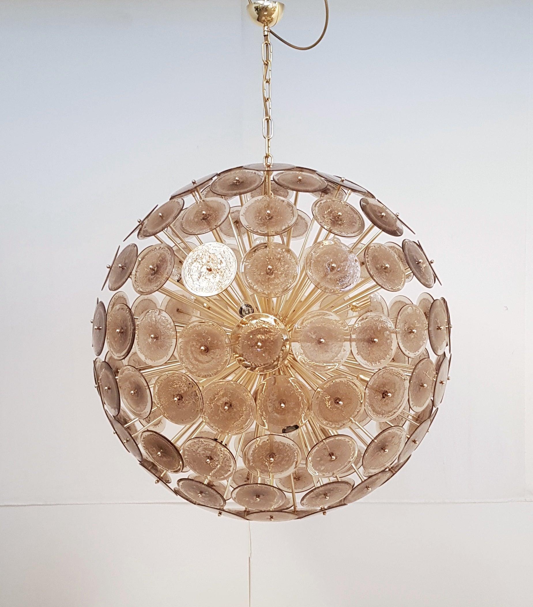 Lustre italien rond en forme de spoutnik avec des disques en verre de Murano brun fumé soufflés à la main avec des bulles selon la technique du Pulegoso, montés sur un cadre en laiton massif en finition polie non laquée qui développera une patine,