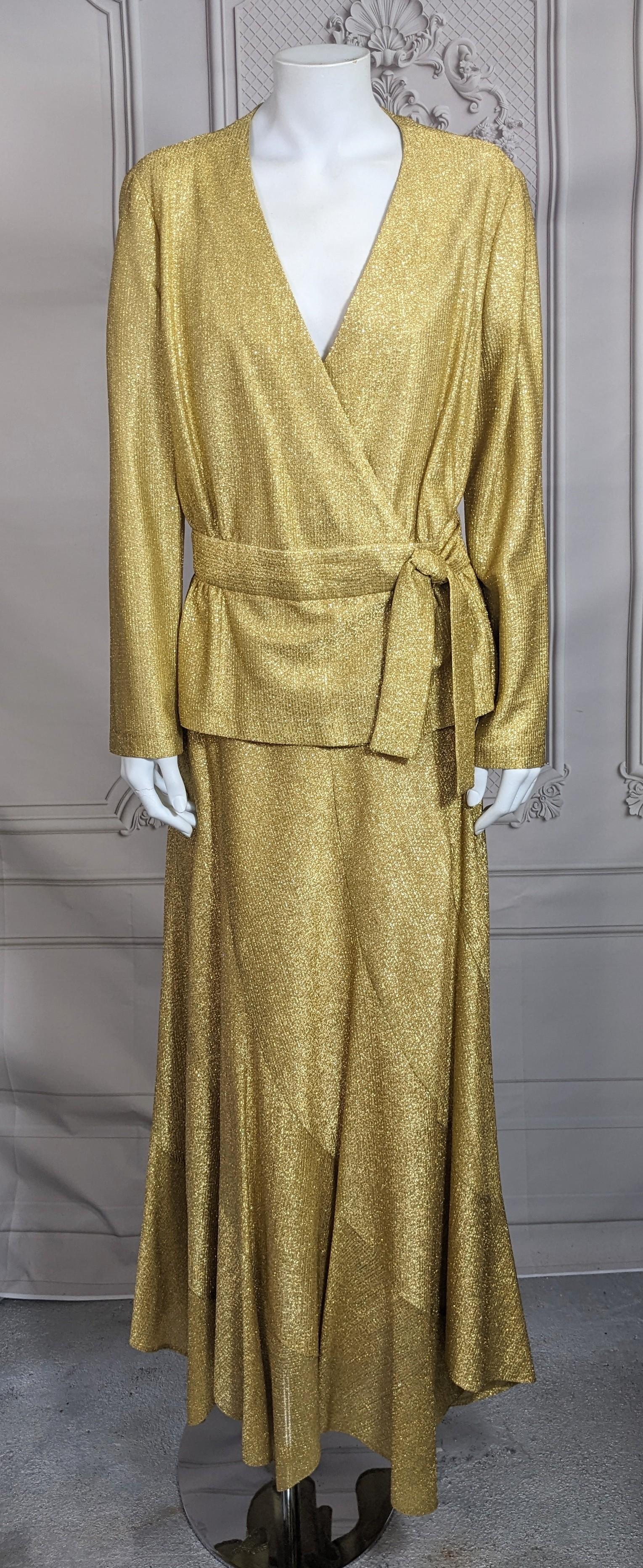 Disco Era Gold Lame Ensemble aus den 1970er Jahren. 2-teilige Wickeljacke mit gewirbeltem, vollem Trompetenrock. Wickeljacke mit eingesetztem Gürtel und Schößchen. Der Rock ist in einem Wirbelmuster geschnitten und hat eine Fülle am Saum, mit