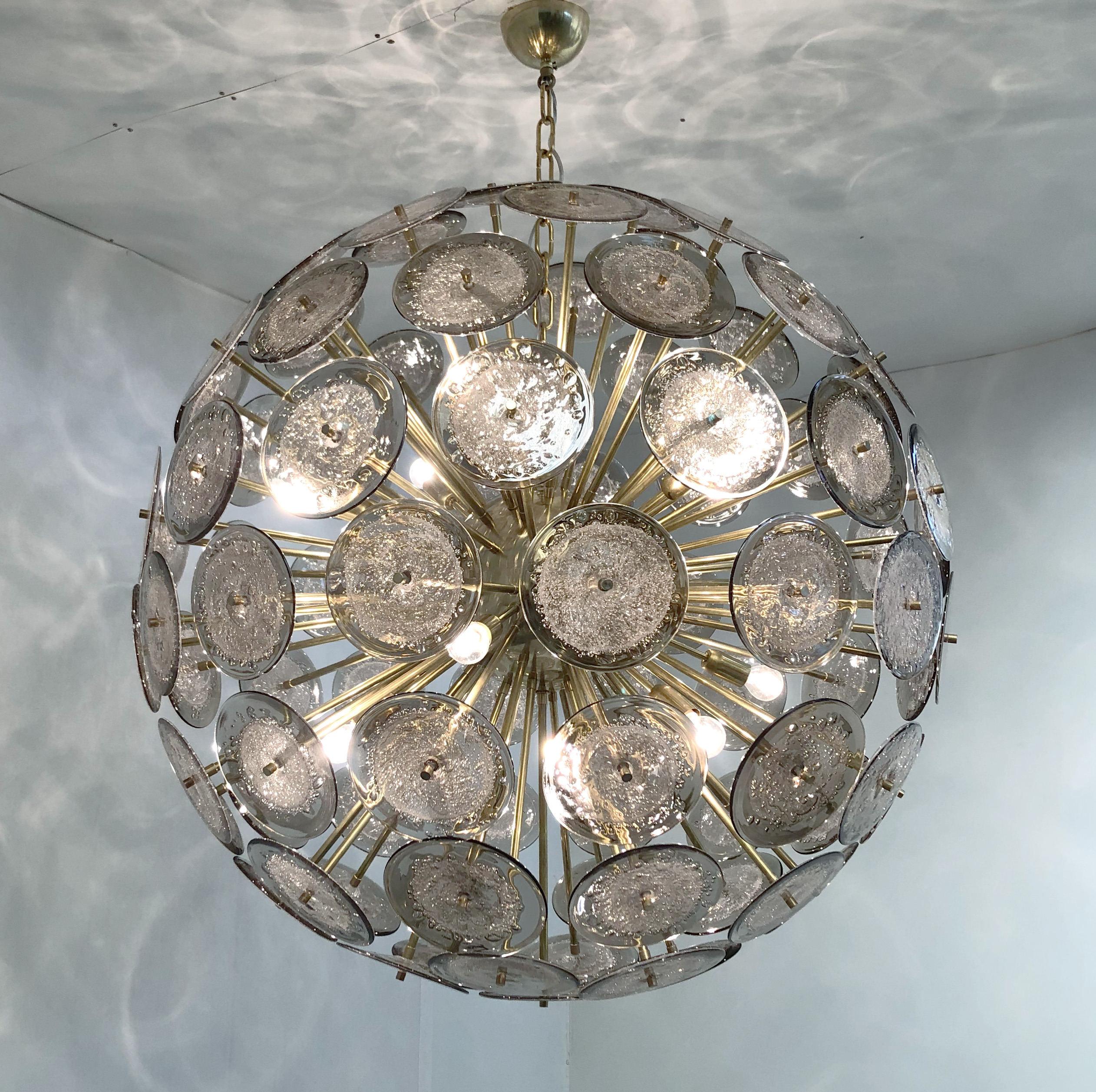 Italian round Sputnik chandelier with smoky gray Murano glass discs hand blown with bubbles using Pulegoso technique, mounted on unlacquered natural brass finish frame which will develop patina, by Fabio Ltd / Made in Italy.
12 lights / E26 or E27