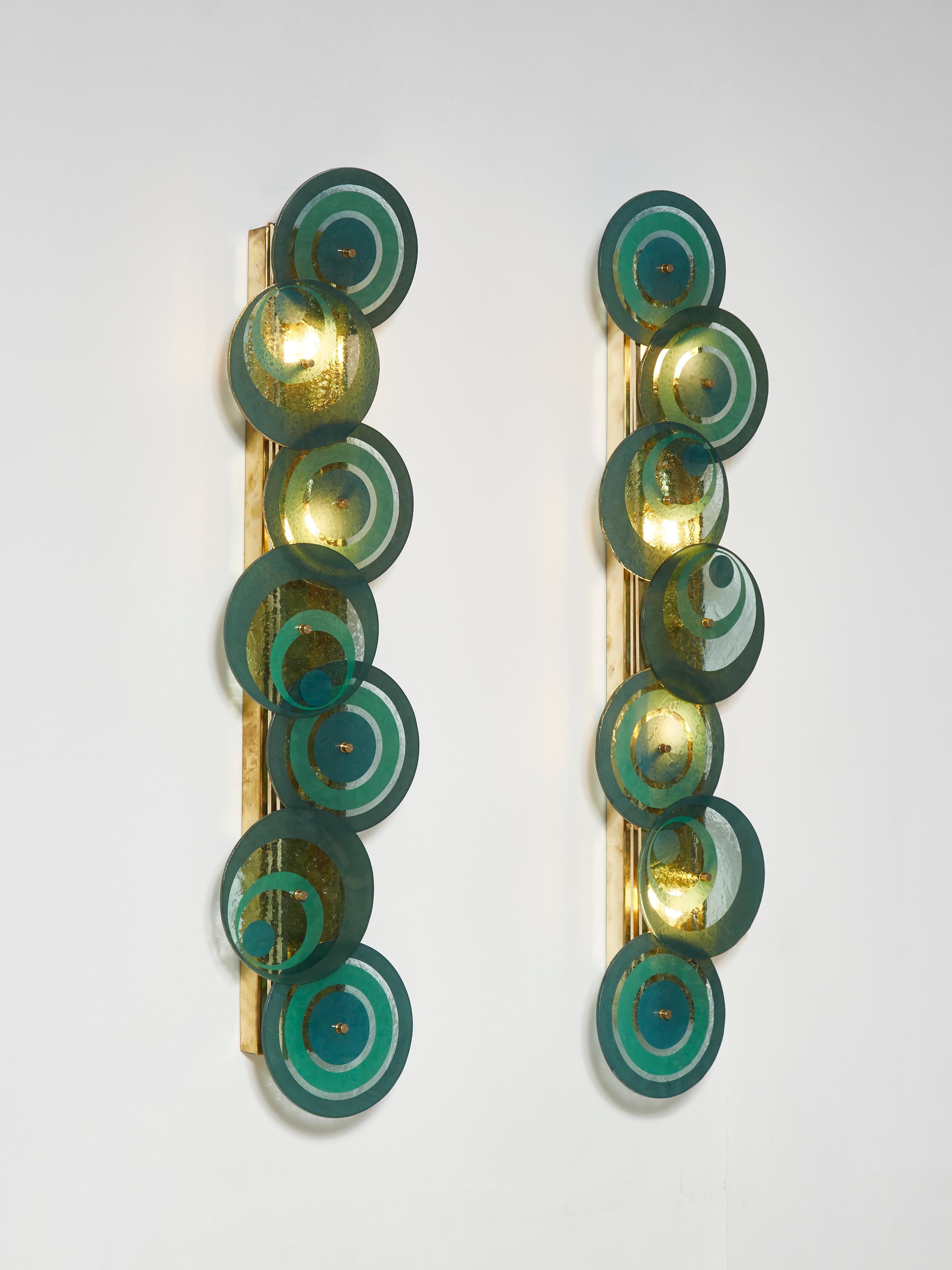 Stunning pair of wall sconces in brass with tainted discs in Murano glass. 4 Light bulbs.
Creation by Studio Glustin.
 