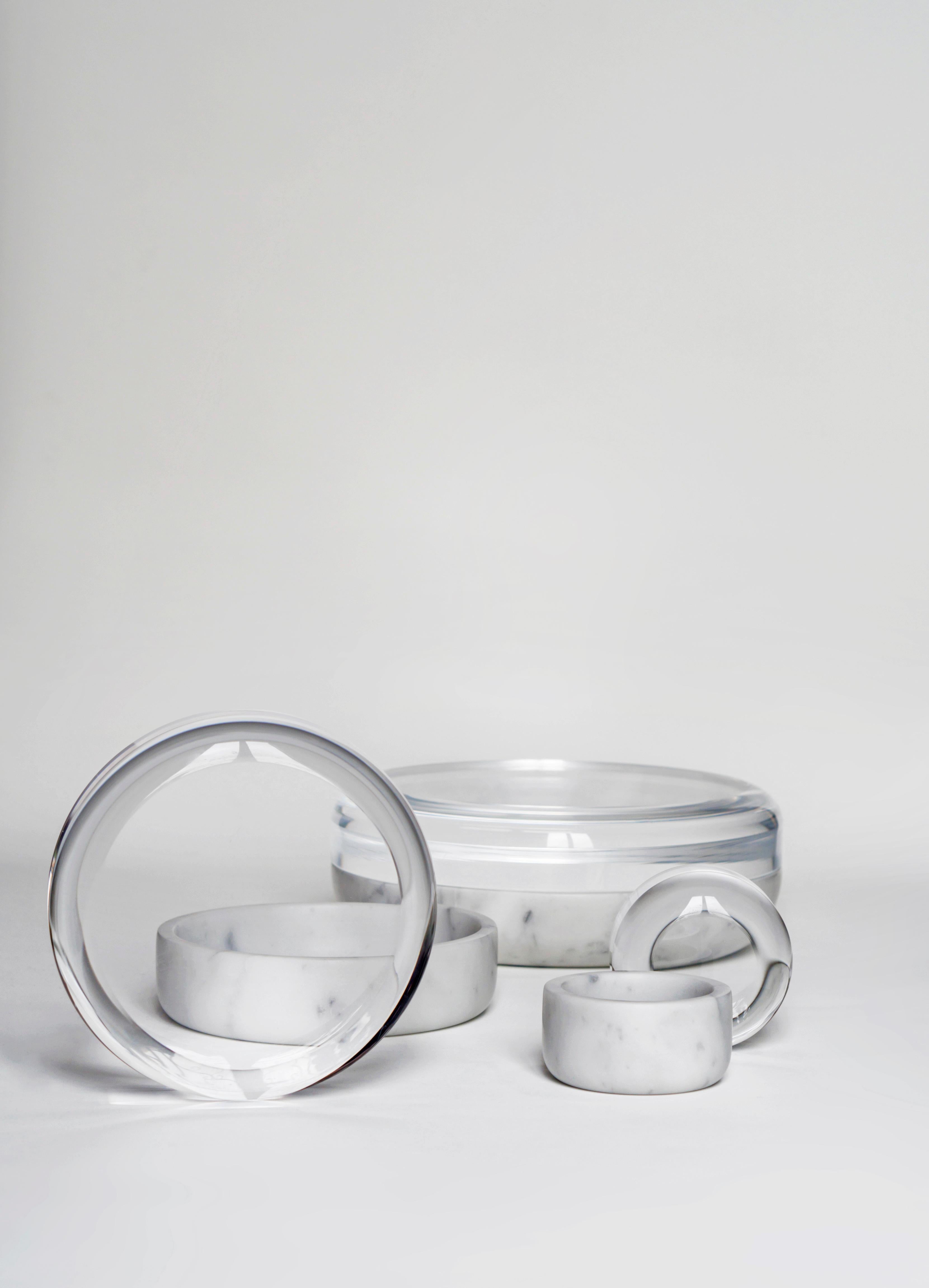 A collection of jewelry holders in white Carrara marble and transparent plexiglas. The content is shown as submerged under the deforming and amplifying ice, as hibernated, timeless. They are precious containers, the eye goes beyond the material and