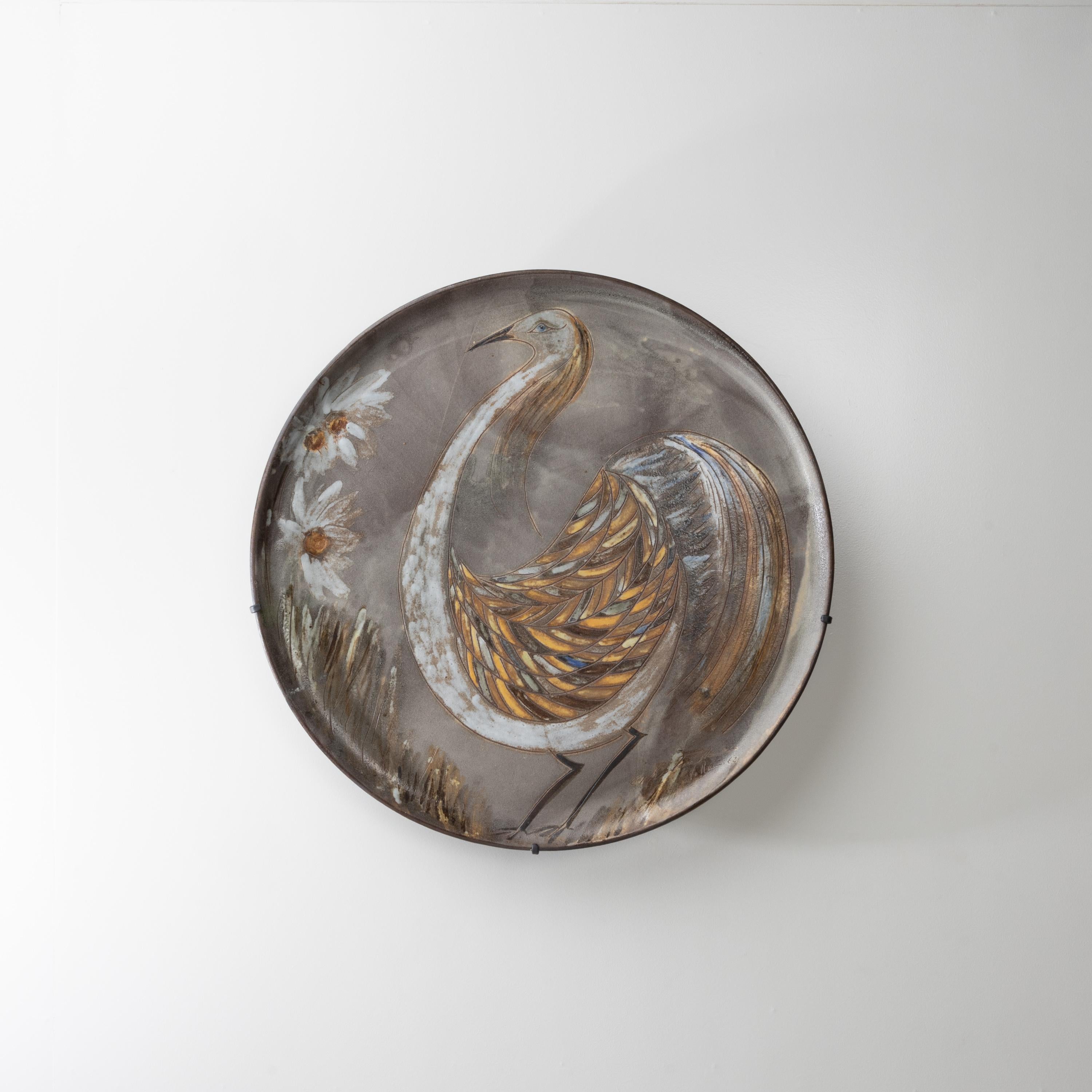Dish by Alexandre Kostanda, glazed ceramic stoneware decorated with a stylized bird.
Very large ceramic dish decorated with a bird and flowers.
The body of the bird incised, decorated in tones of beige, amber, brown, gray and blue.
A decoration of