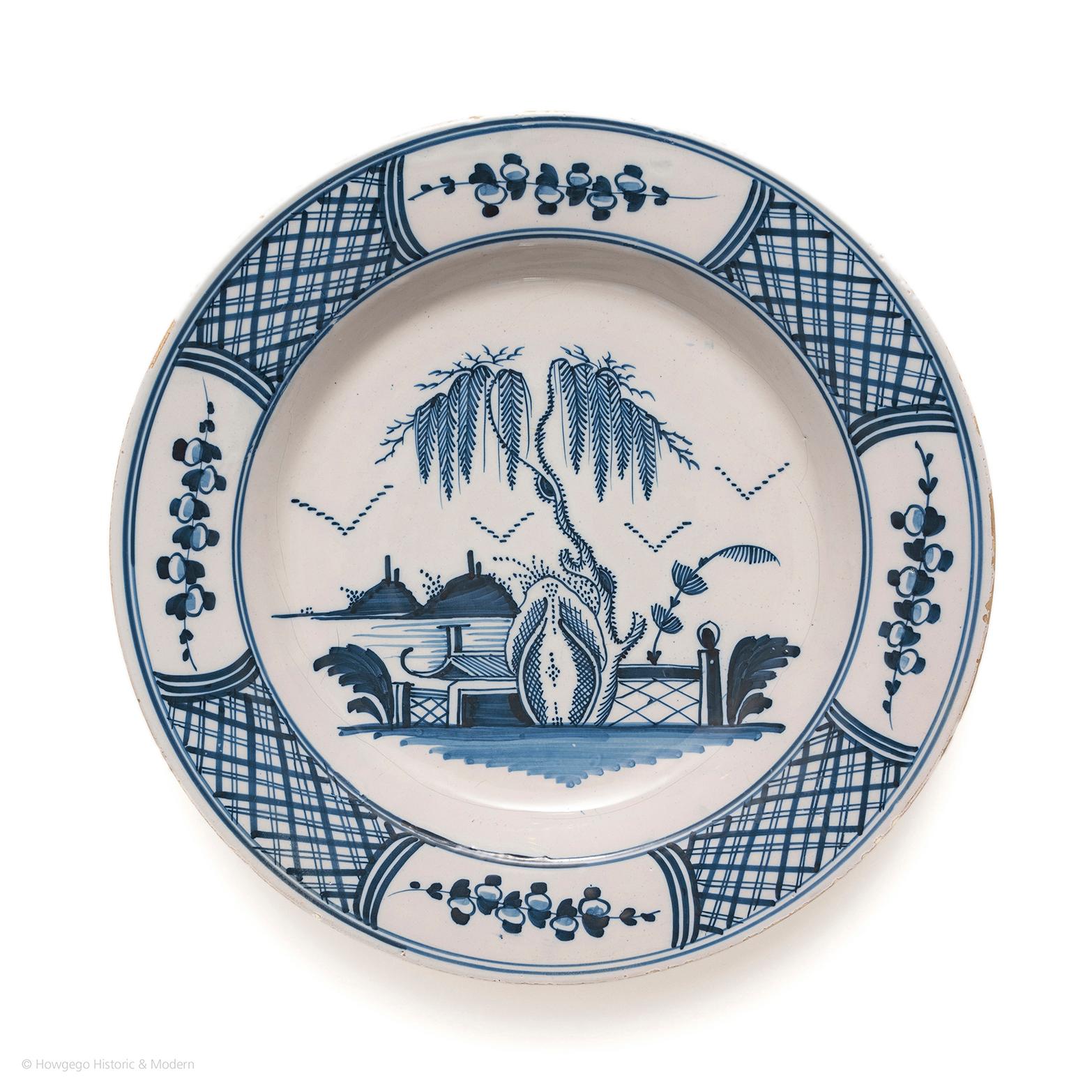 Delightful, charming chinoiserie dish conveying the European interpretation of and fascination with exotic Chinese plants and landscape. 

Decorated with a large willow tree and stylised rockwork outside a fenced garden with hills in the distance