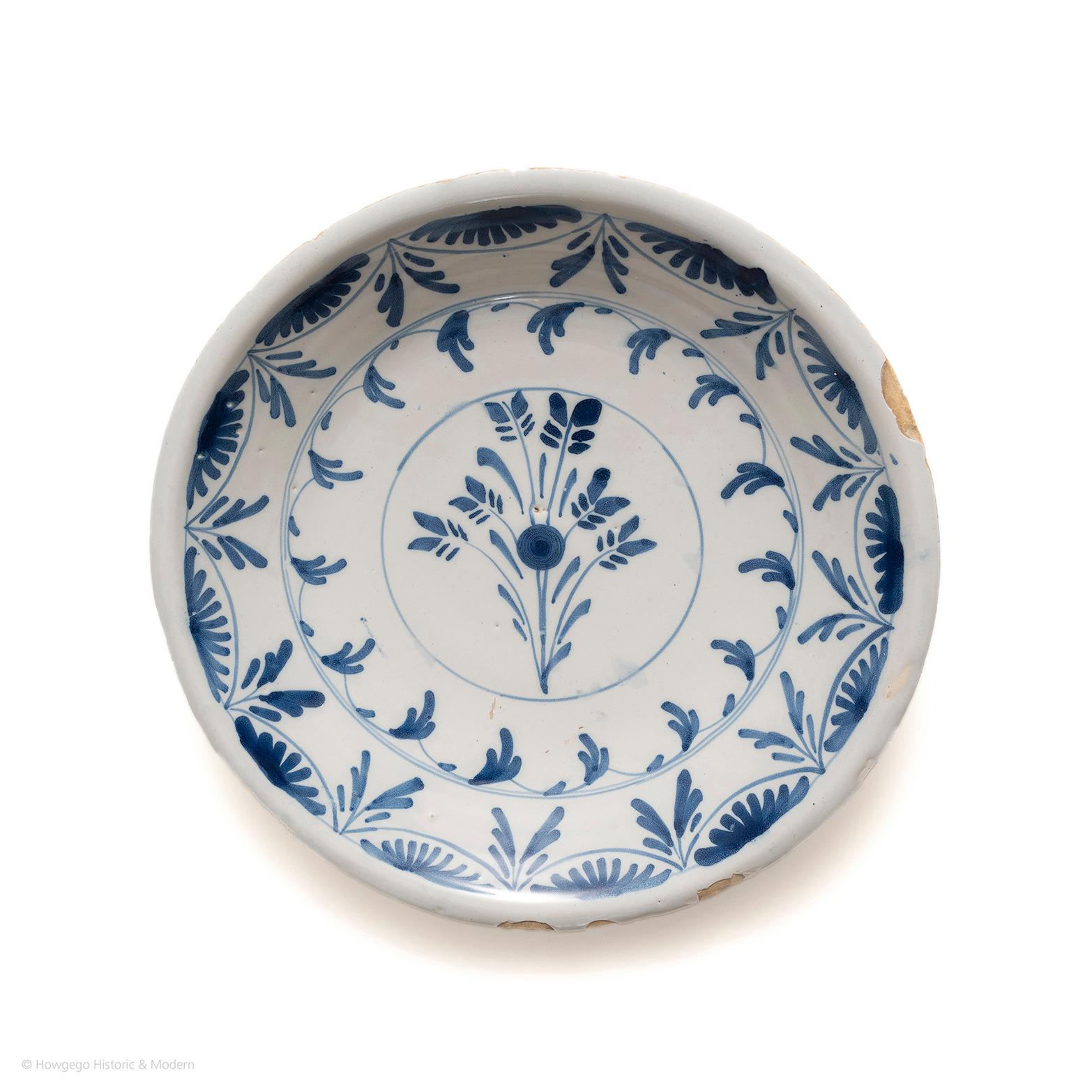 Beautiful, early stylised decoration evoking the striking simplicity of early Chinoiserie painting

Painted with a central floral spray within a circle centre, surrounded by a trailing leaf border within a stylised leaf border. Painted in blue on