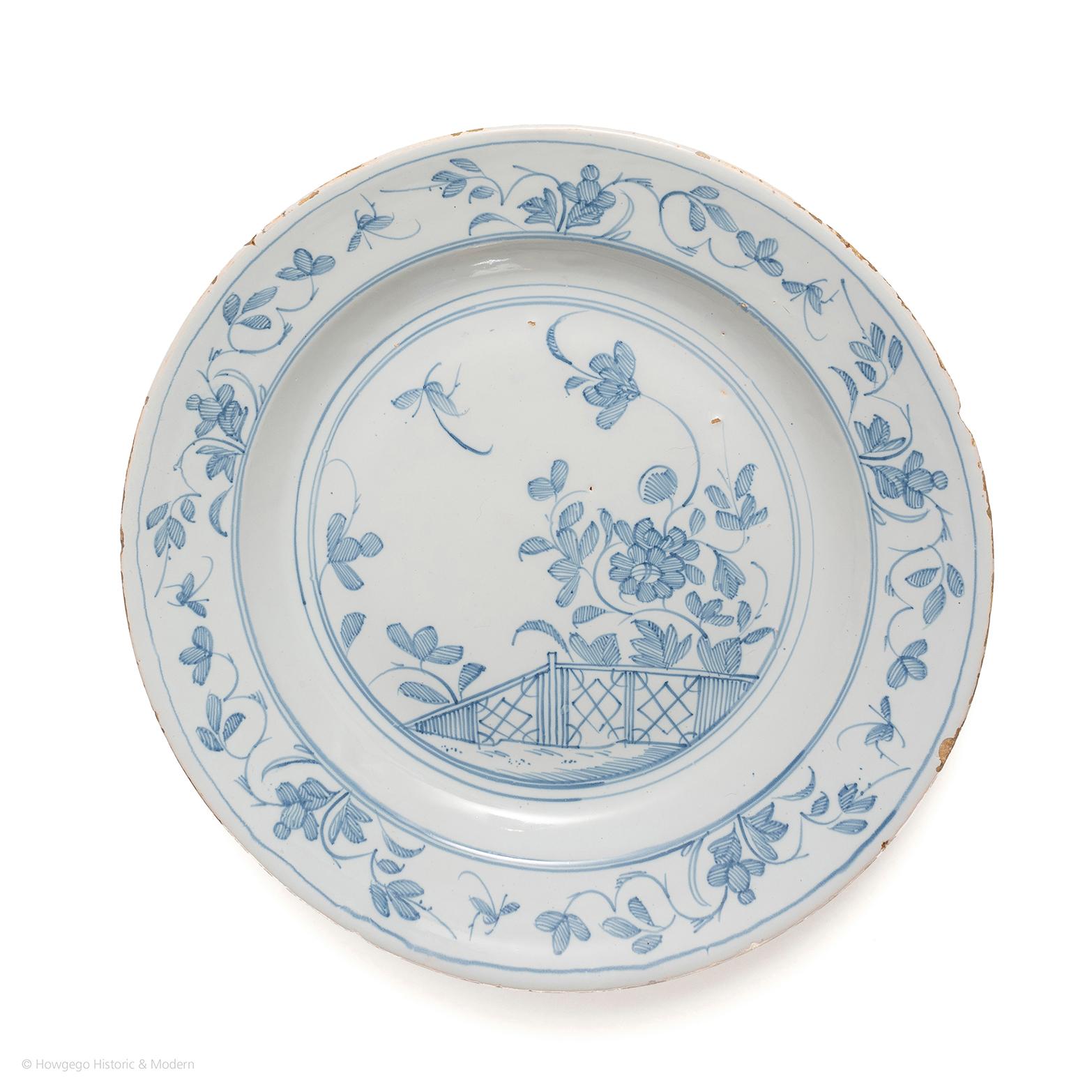 Delightfully painted in soft tones of blue conveying the lightness and charm of Chinoiserie.

Painted with a chinoiserie landscape scene of a large peony growing behind a fence with a butterfly flying above. The rim with five floral sprays