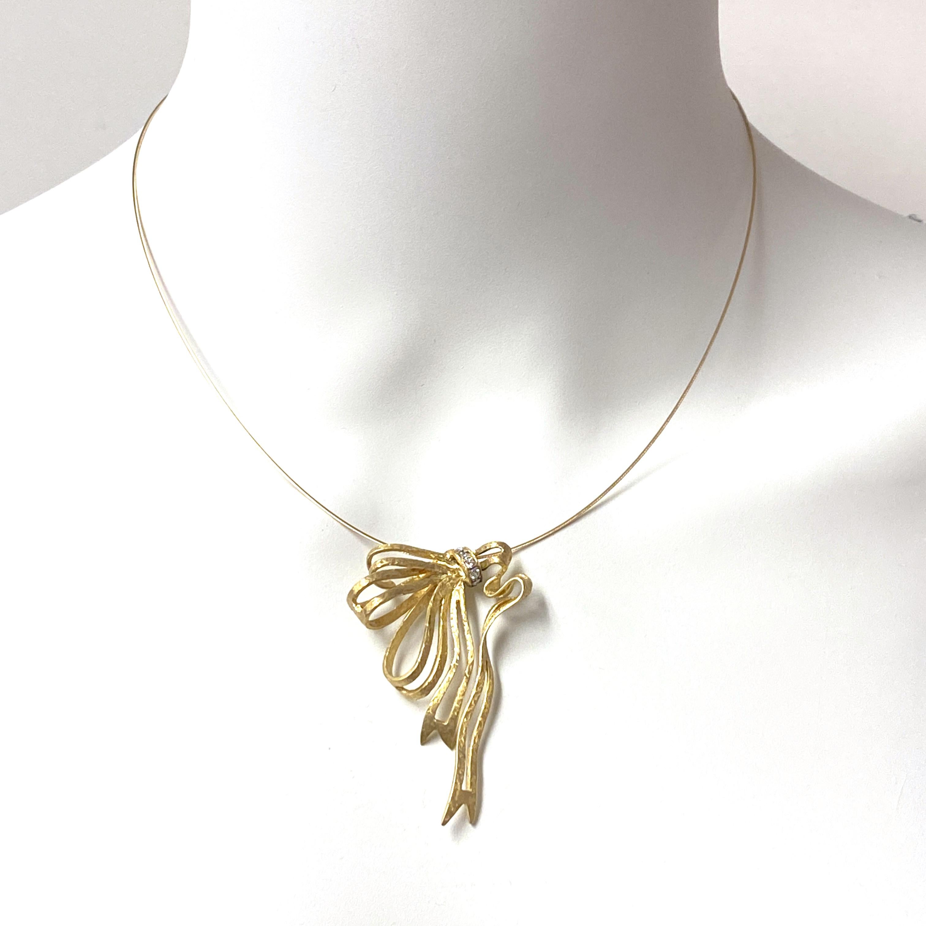 This lovely and unusual 18 karat gold pendant is cast in the shape of a gracefully unraveling ribbon.  The suggestion of diaphanous, flowy fabric is enhanced by the pendant's sanded and hammered finish.  As a final touch, the center is set with six