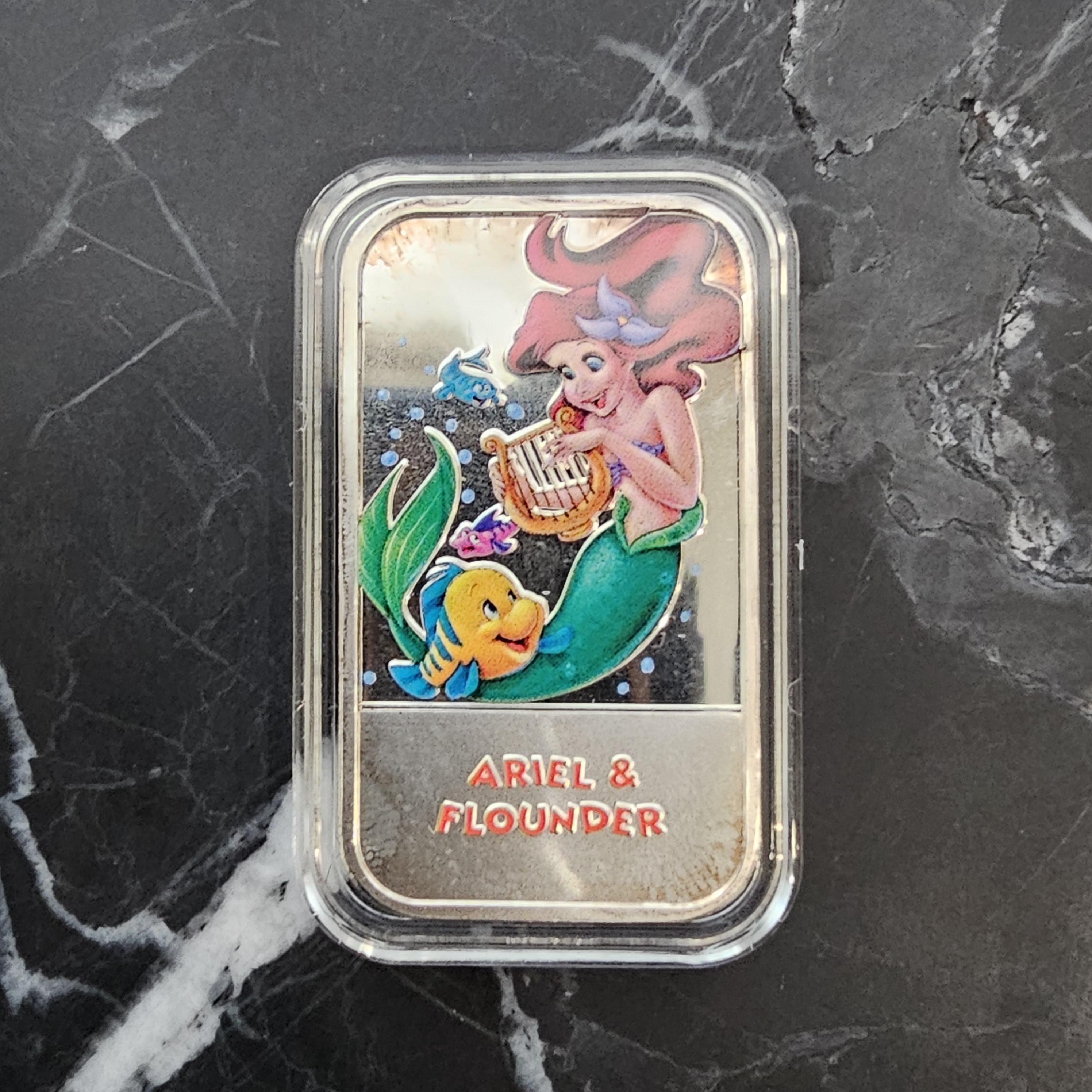 Rehaussez votre collection avec ce captivant lingot d'argent 999 1oz de Disney's Little Mermaid Ariel & Flounder. Fabriquée avec précision, cette pièce présente des illustrations émaillées vibrantes des personnages bien-aimés de 