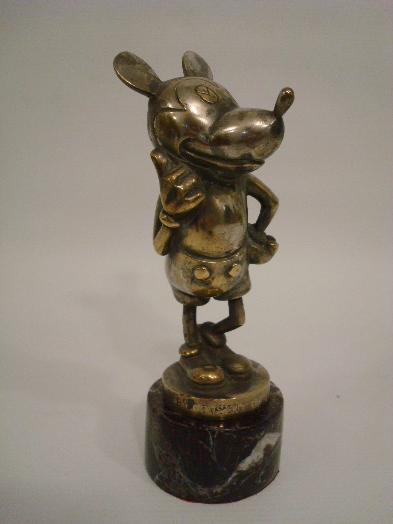 A rare Mickey Mouse car mascot, British, circa 1930, made of bronze Nickel plating, with engraved inscription around the base 'Reproduced By Consent of Walter E. Disney', depicting the film star in jaunty pose, one hand on hip the other giving