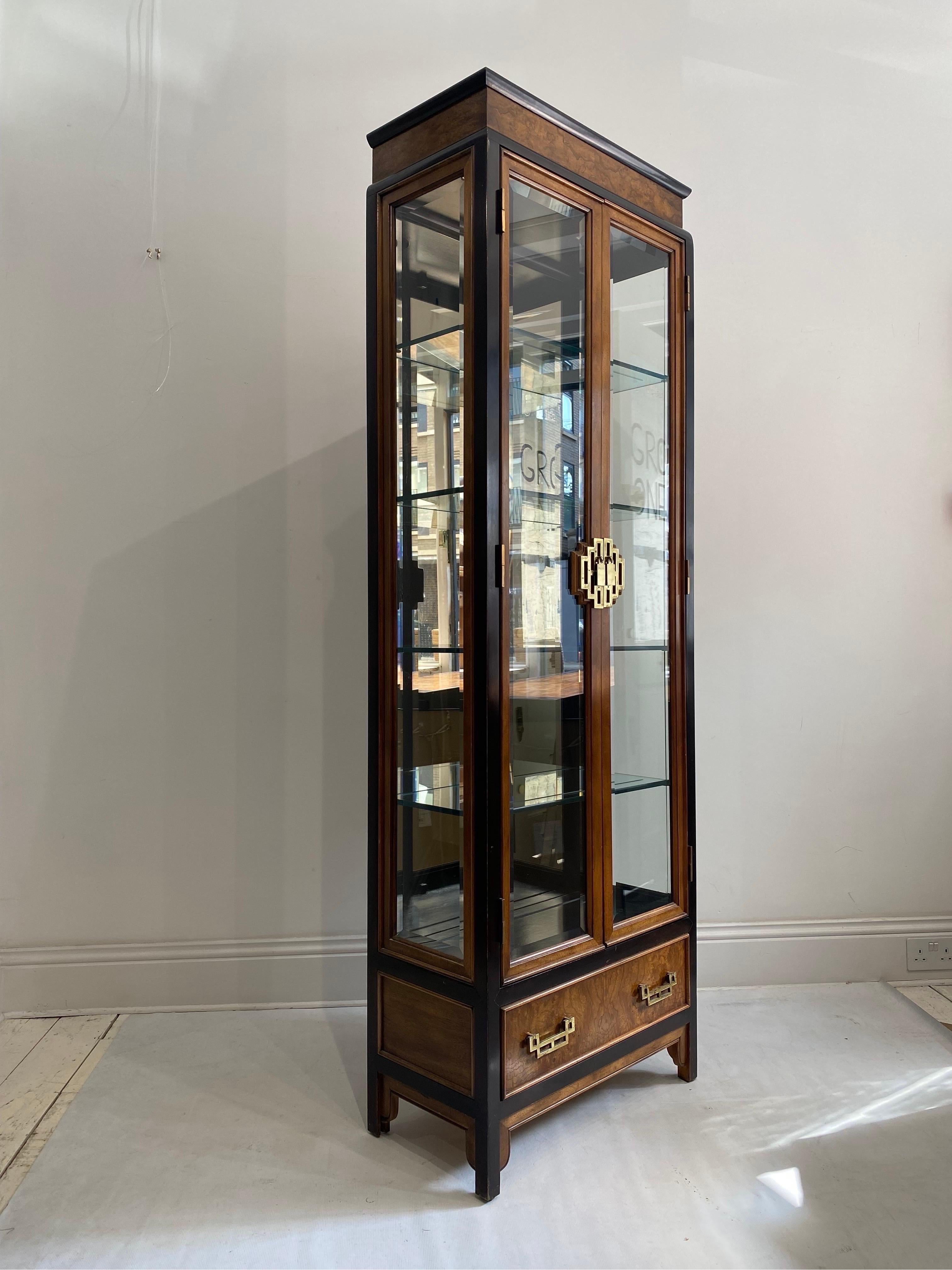 This impressively tall display glass and mirror cabinet framed in burl and brass finish details by Raymond Sobota for Century Furniture Of Distinction from his Chin Hua collection is a rare UK import. Although Century Furniture were popular in USA,