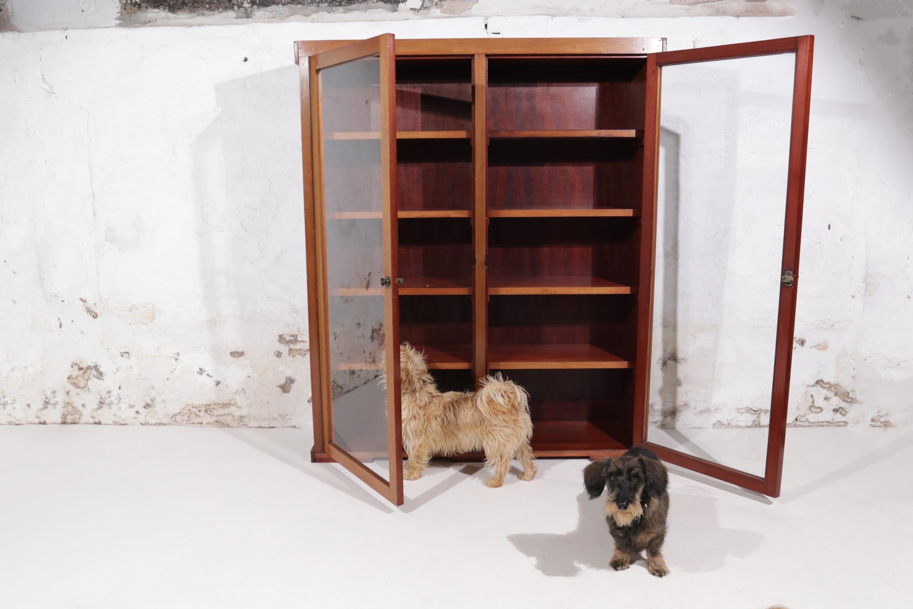 Sleek minimalist design display cabinet or bookcase with glass doors from the 1950s.
The glass is the beautiful old drawn glass and the closing buttons have a nice patina.
The cabinet is in very nice condition.

The planks are 52 cm wide and 26