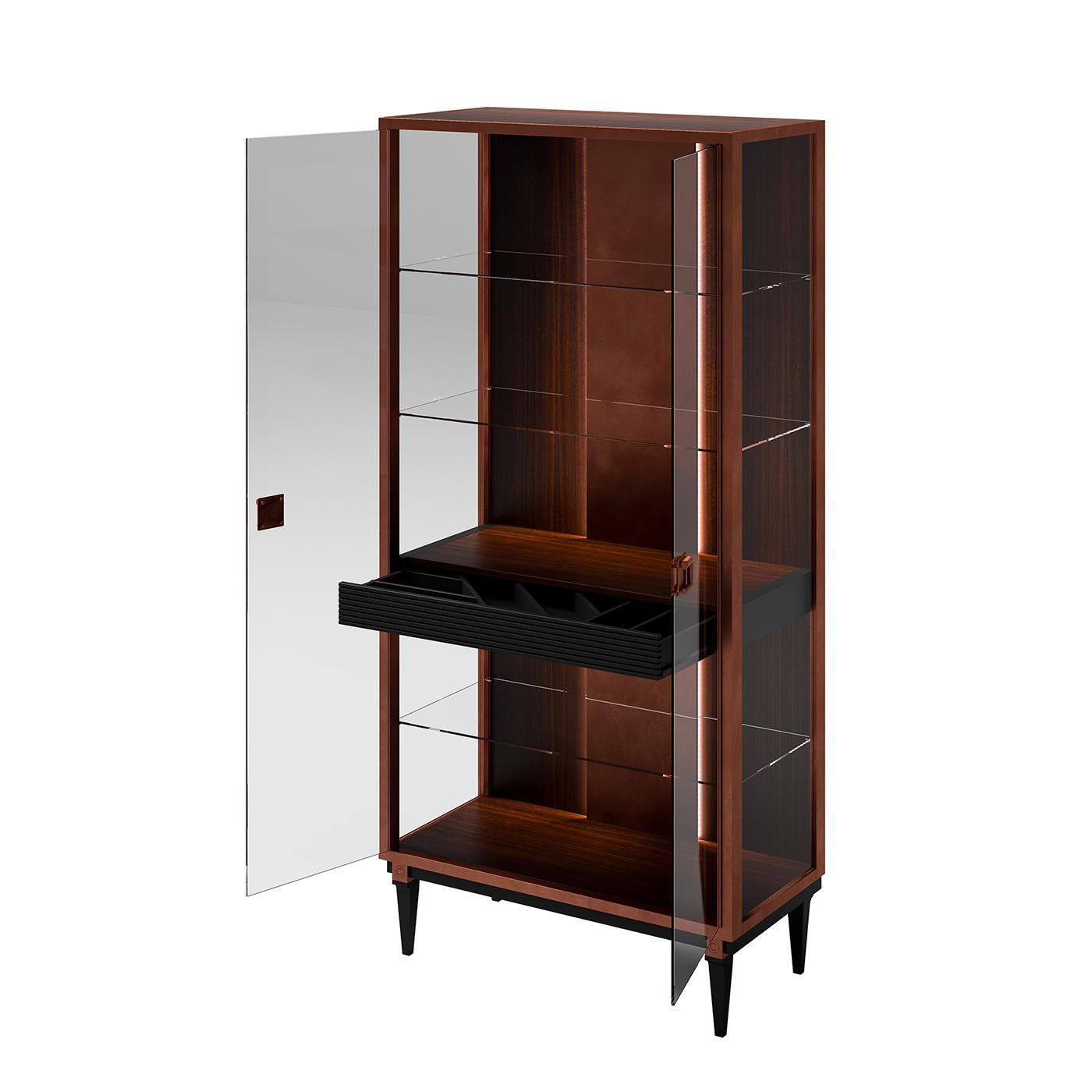 Inspired by the traditional china cabinets, this sophisticated display cabinet features a rectangular frame of forest eucalyptus veneer raised on four tapered legs with a black finish. Both sides and doors have glass panels. Inside the cabinet is
